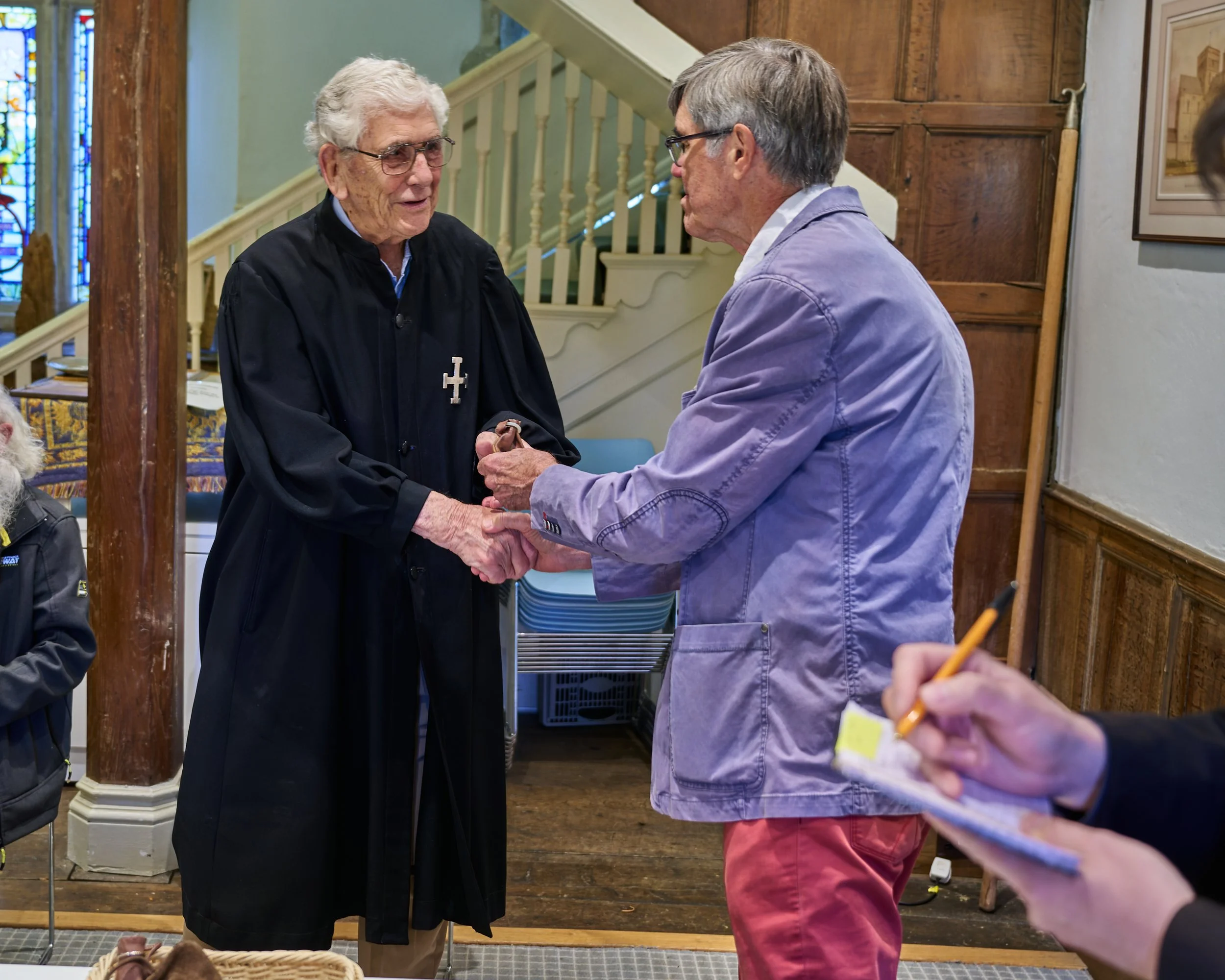 This documentary fieldwork photograph shows a traditionally robed Brother receiving his money pouch during the symbolic continuance of Friday Pay Parade at the Hospital of Saint Cross.