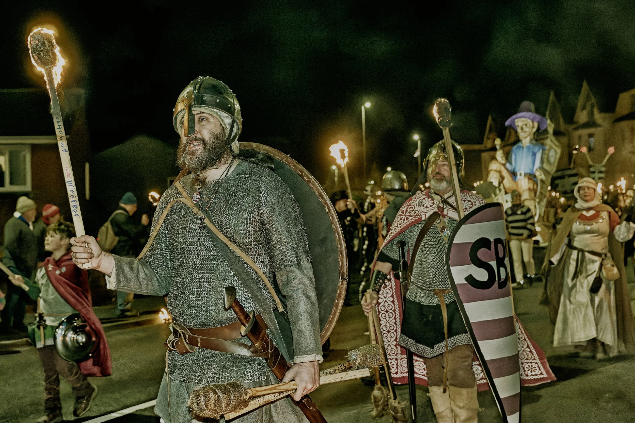 Documentary fieldwork photograph of a Sussex Bonfire Society parade in Seaford, showing the Saxons with flaming torches
