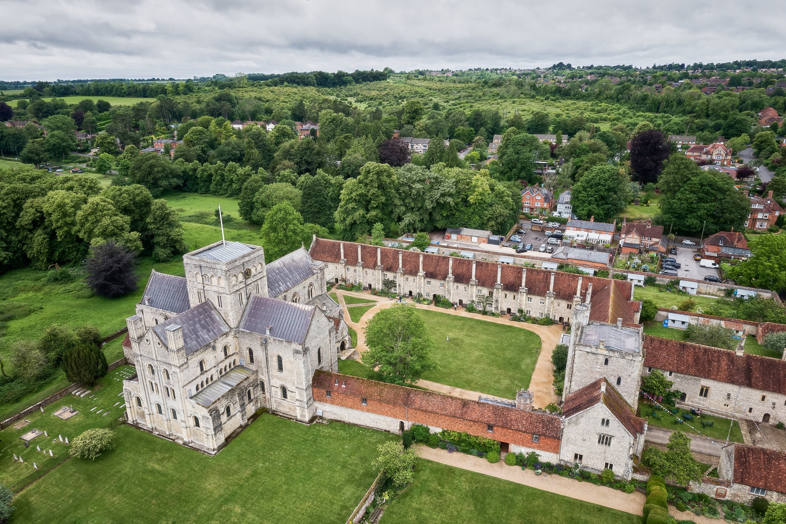 This documentary fieldwork photograph provides an aerial view of the Hospital of Saint Cross Church, Winchester: its Church, Ambulatory, Beaufort’s Tower, and Almshouses.