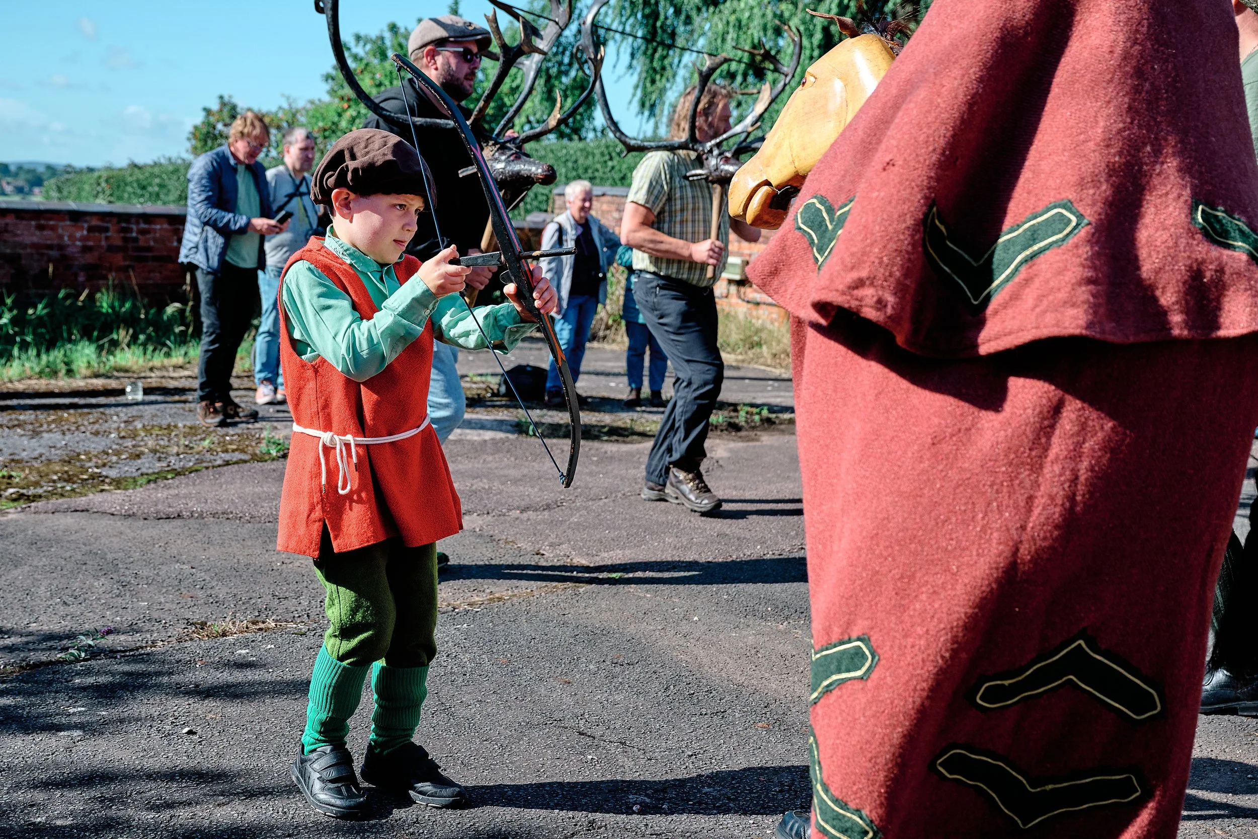 Documentary fieldwork photograph of the Horn Dance event in Abbots Bromley, showing the child Robin Hood with bow and arrow