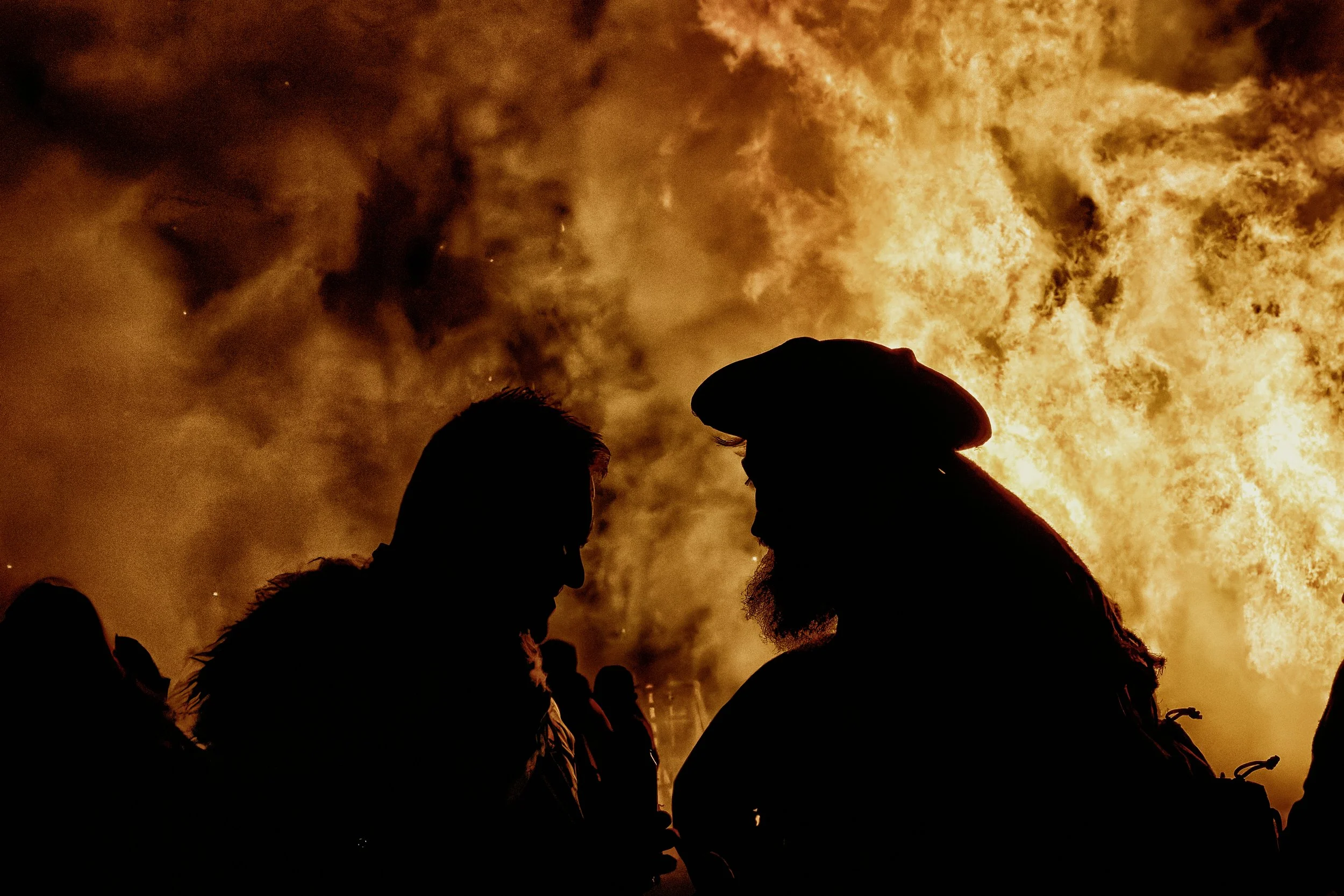 Documentary fieldwork photograph of a Sussex Bonfire Society parade in Seaford, showing the participants lit by an inferno bonfire
