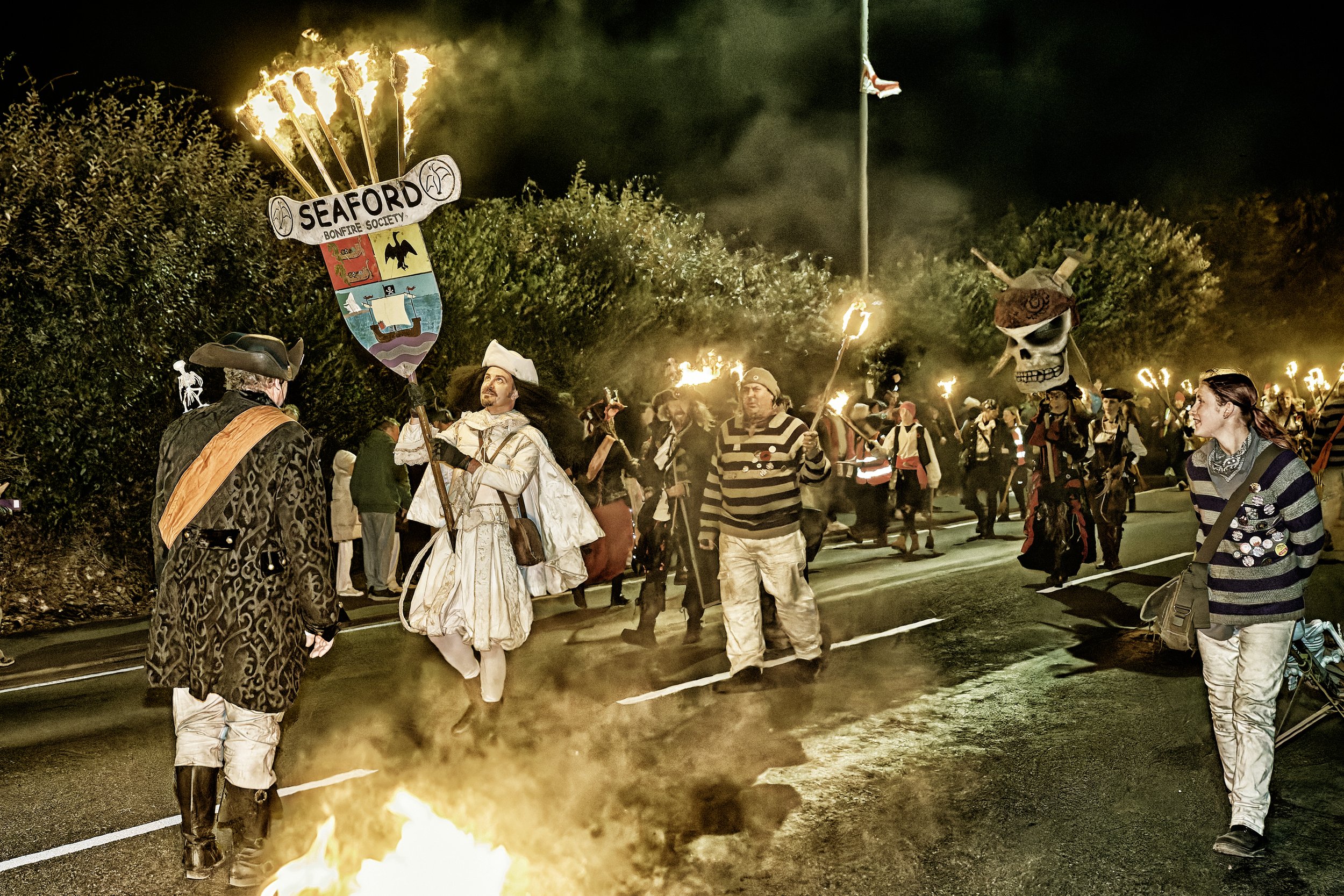 Documentary fieldwork photograph of a Sussex Bonfire Society parade in Seaford, showing the Lord Monteagle with Smugglers holding flaming torches