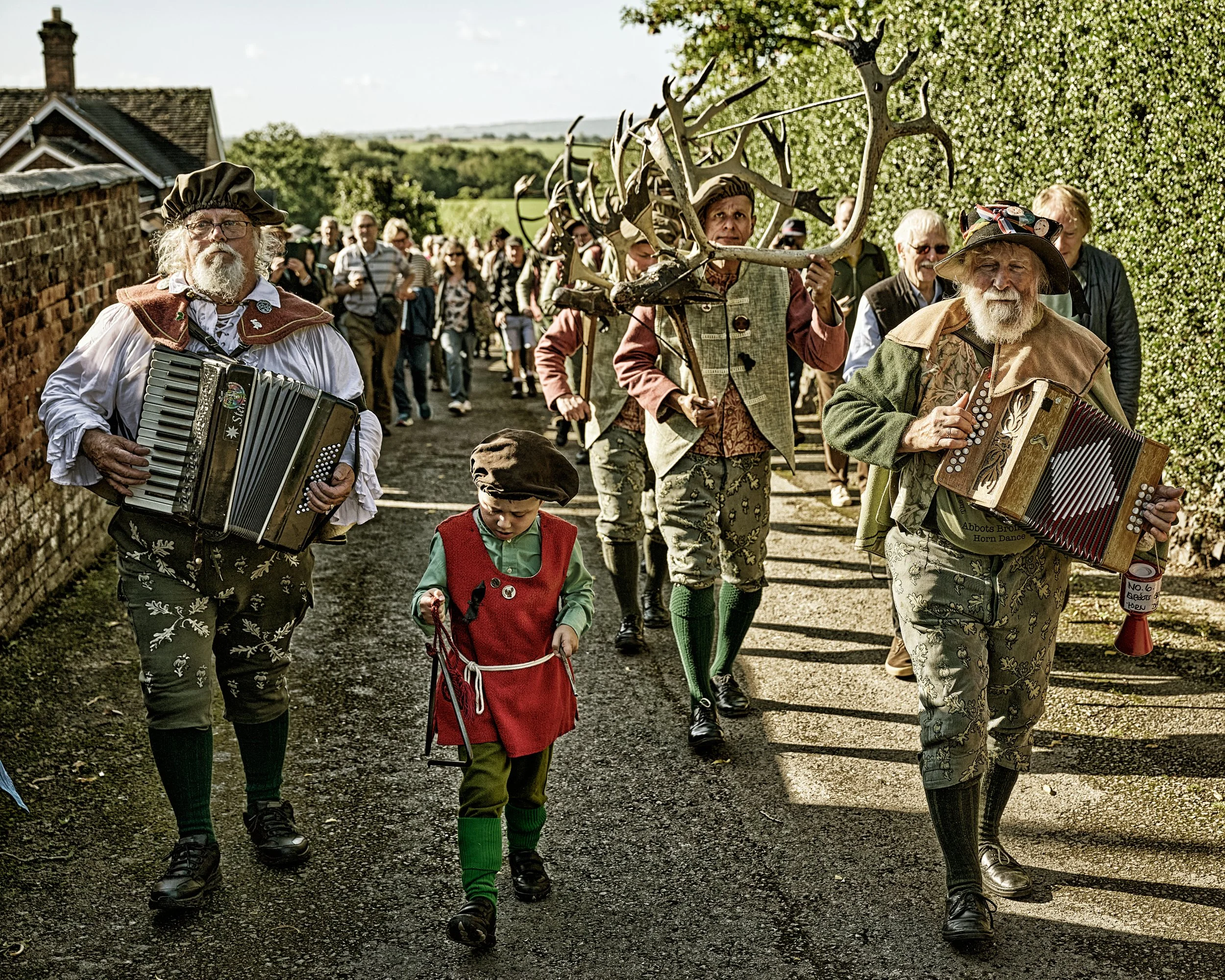 Documentary fieldwork photograph of the Horn Dance event in Abbots Bromley, showing musicians and horn dancers with their 1000 years old antlers in parade