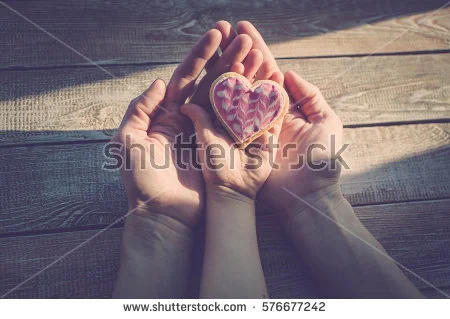 stock-photo-female-and-children-s-hands-hold-cookies-in-the-form-of-heart-on-a-wooden-table-top-sunlight-a-576677242.jpg