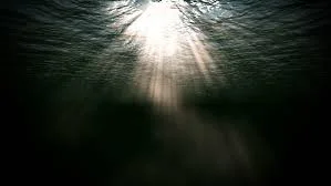 Sunlight shining down through water, creating rays and reflections.