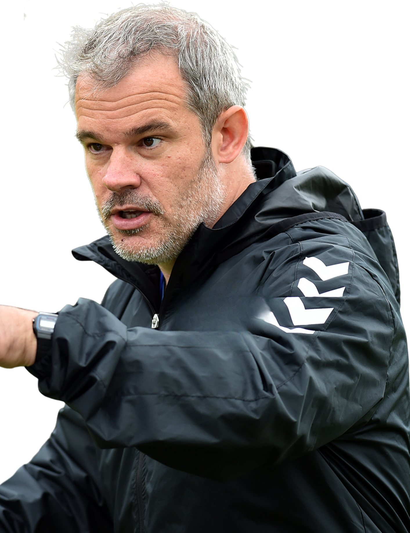 A middle-aged man with gray hair and a beard, wearing a black jacket with white lettering on the sleeve, appears to be outdoors and is looking at something off-camera.
