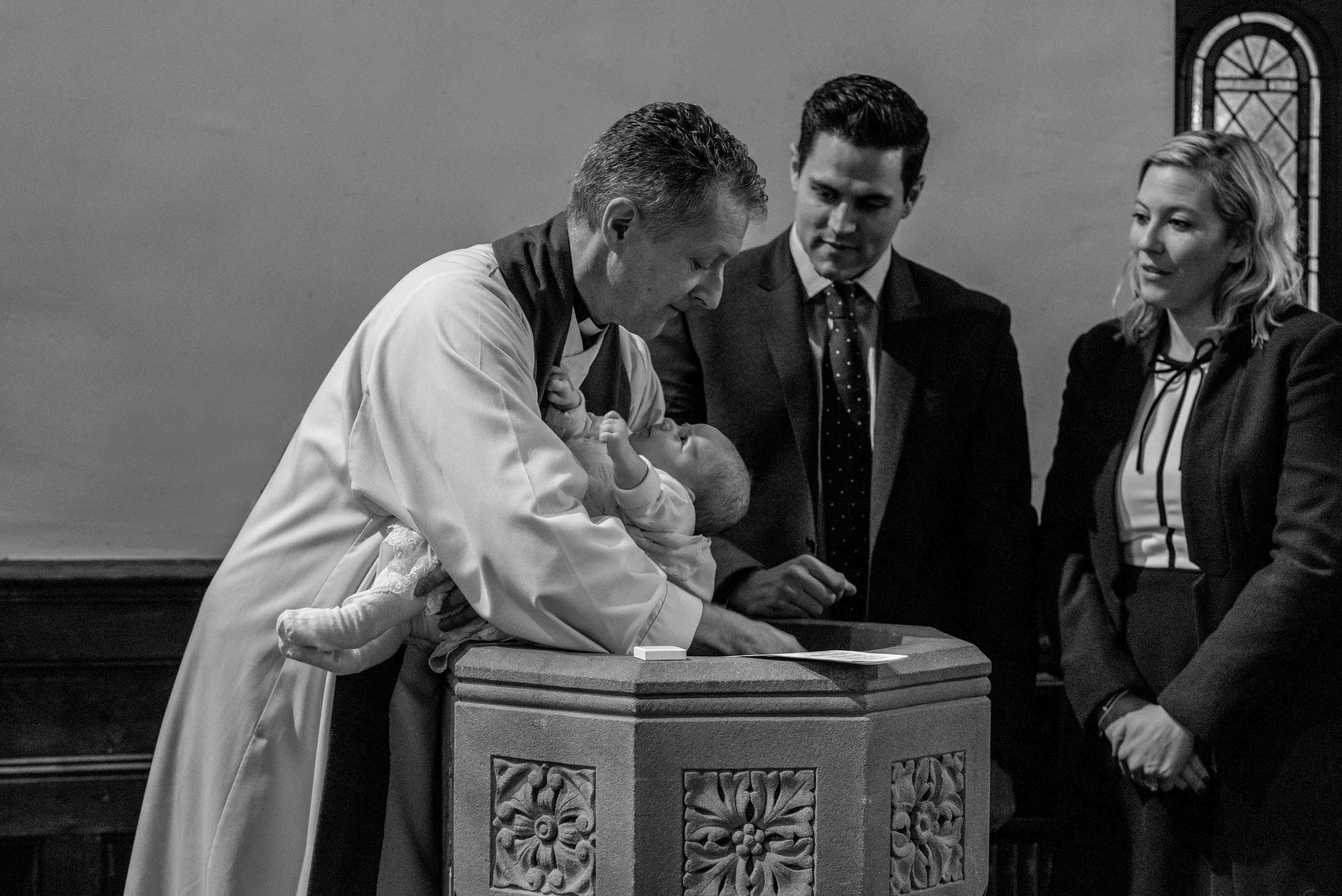 The vicar Christens baby Harry in the front at the rear of the church.