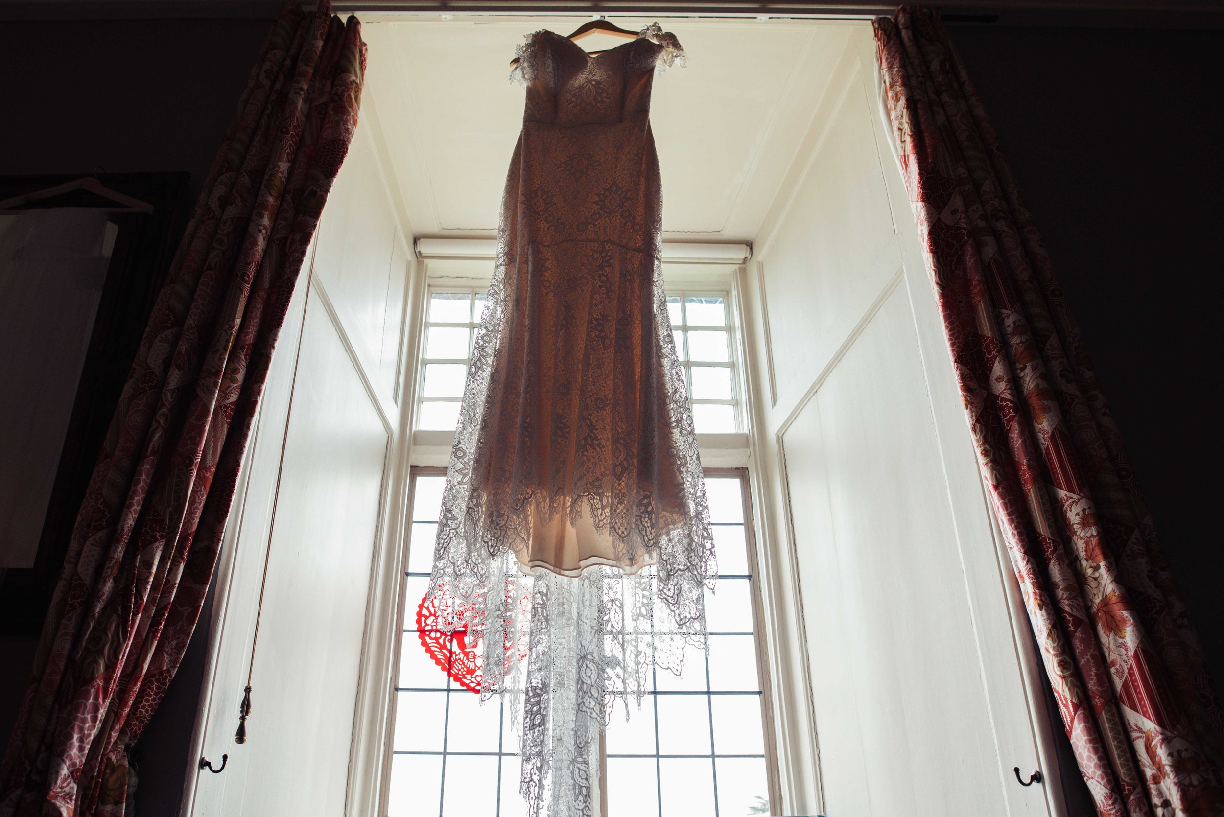 The brides dress hangs in a window at Askham Hall