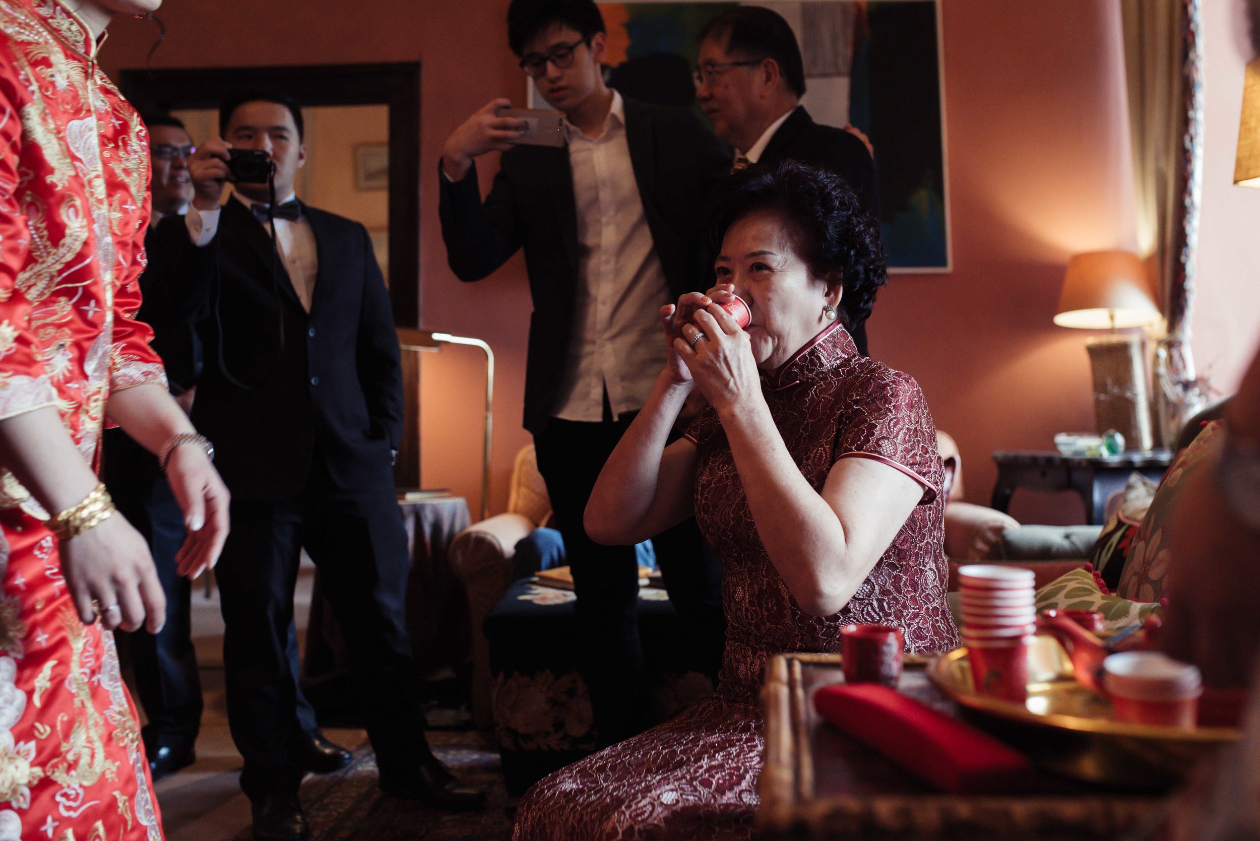 The brides mother drinks her tea during the tea ceremony