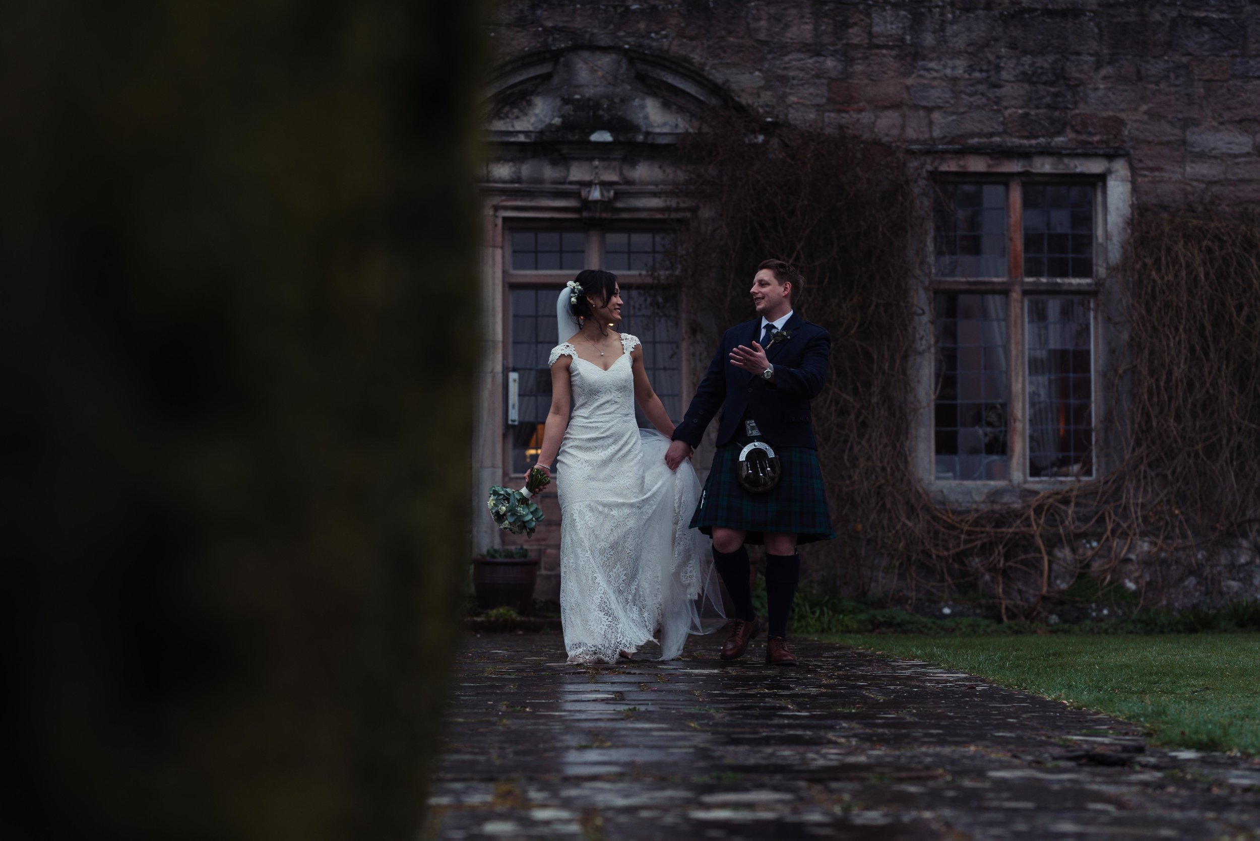 The bride and groom have a chat with each other as they walk away from Askham Hall