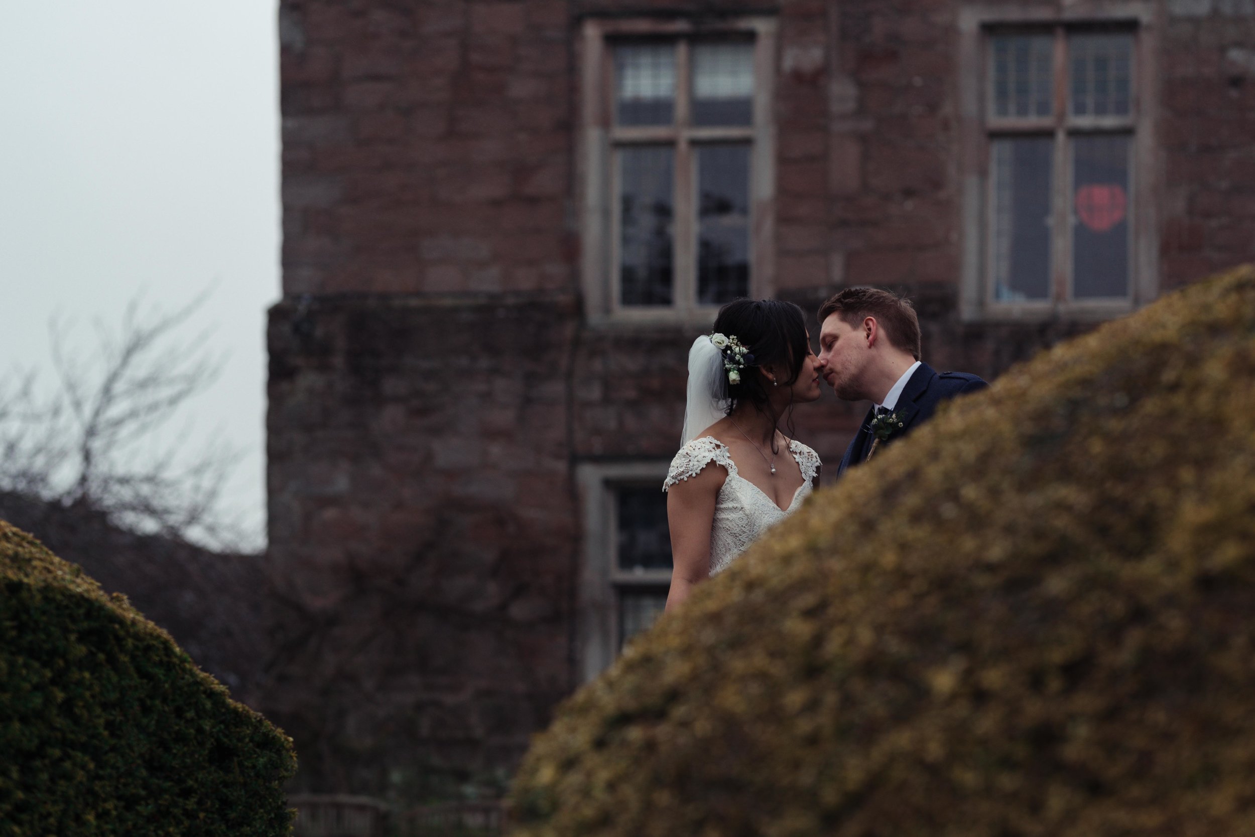 The bride and grooms head are visible above a bush at Askham Hall