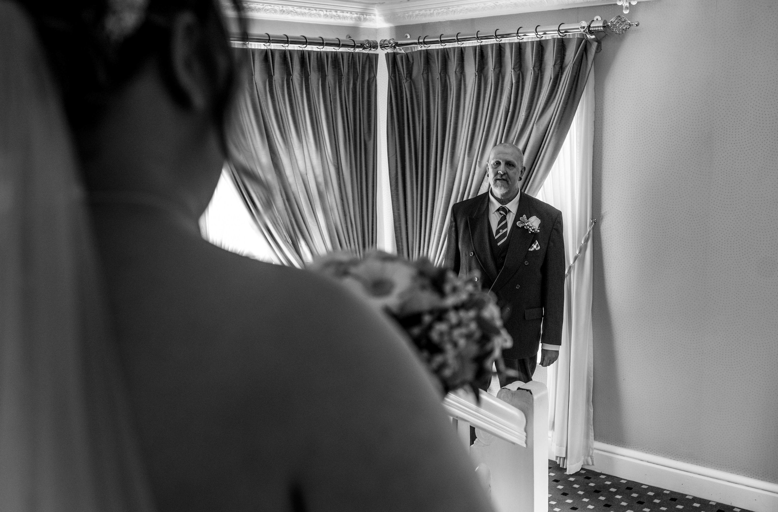 A view over the brides shoulder of the father of the bride seeing her for the first time.