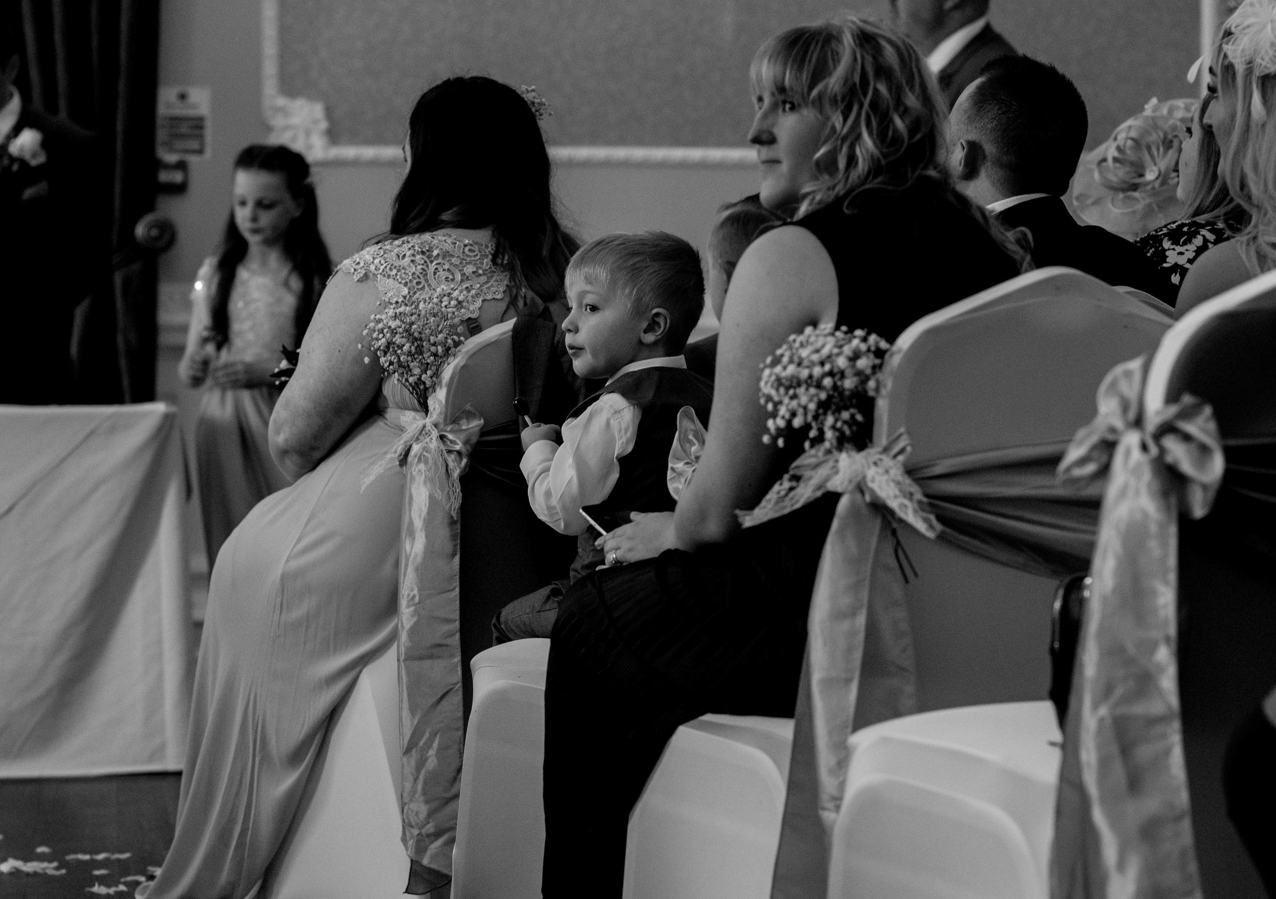 A young page boy sits quietly during the wedding ceremony