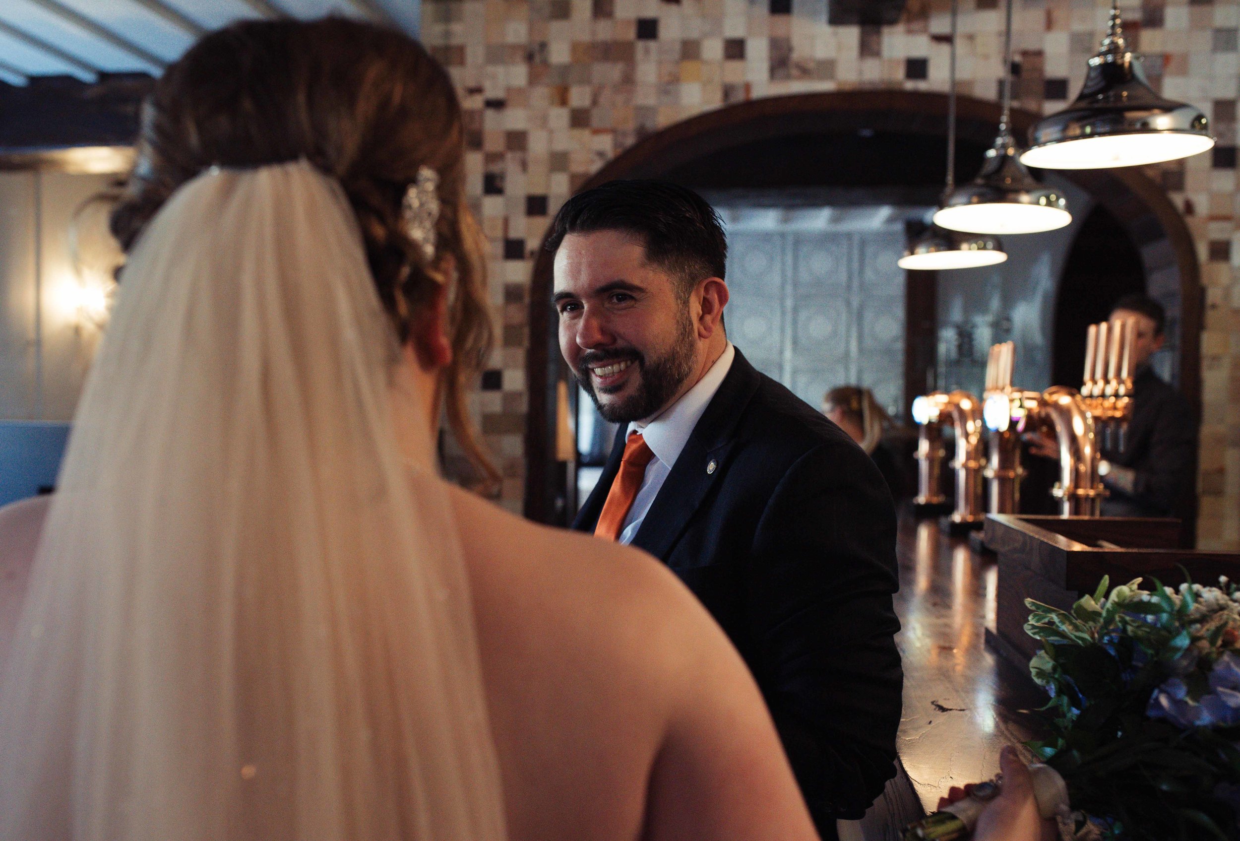 Male wedding guest stands at the bar and chats with the bride