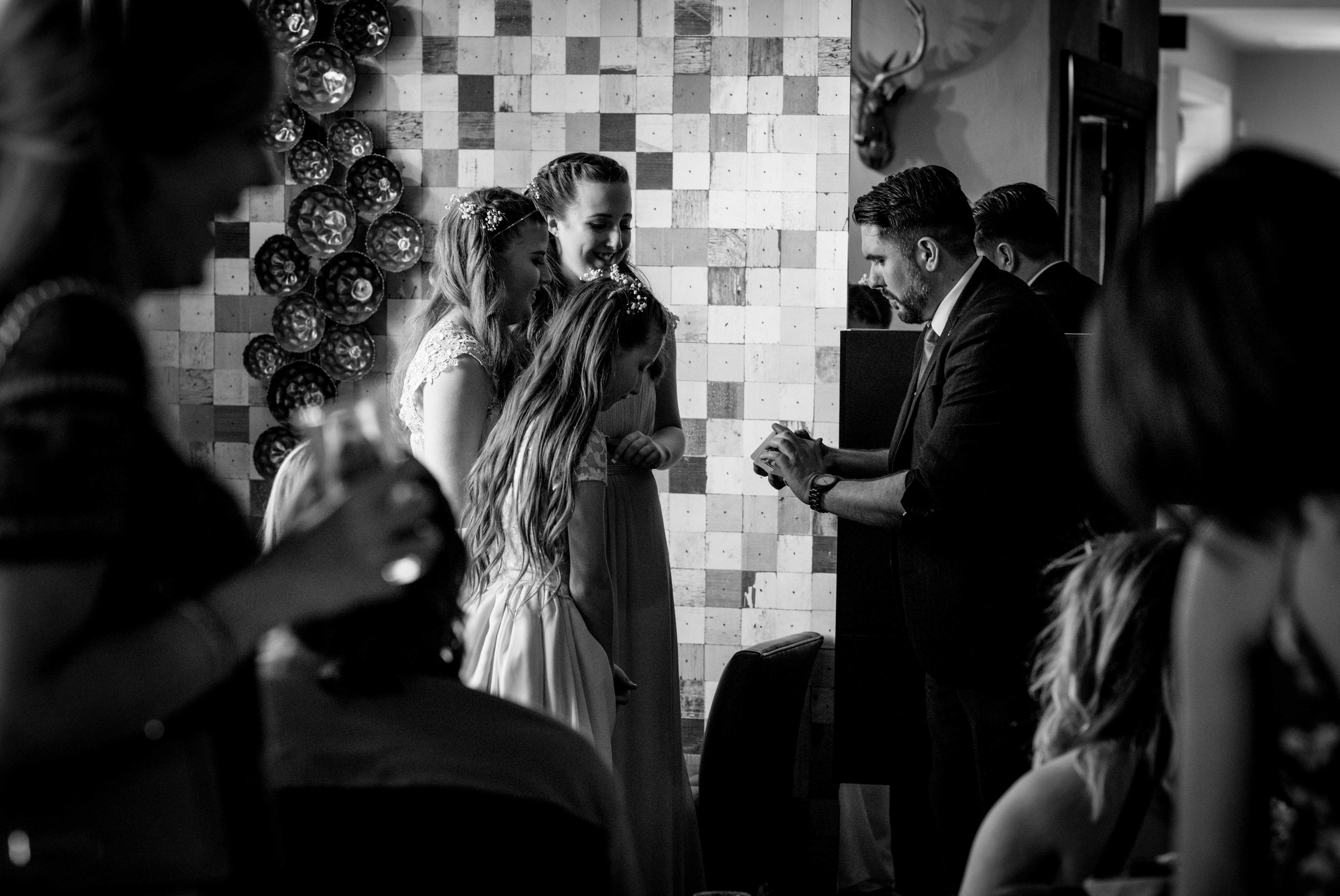 The young wedding guests watch with amazement the magician doing card tricks