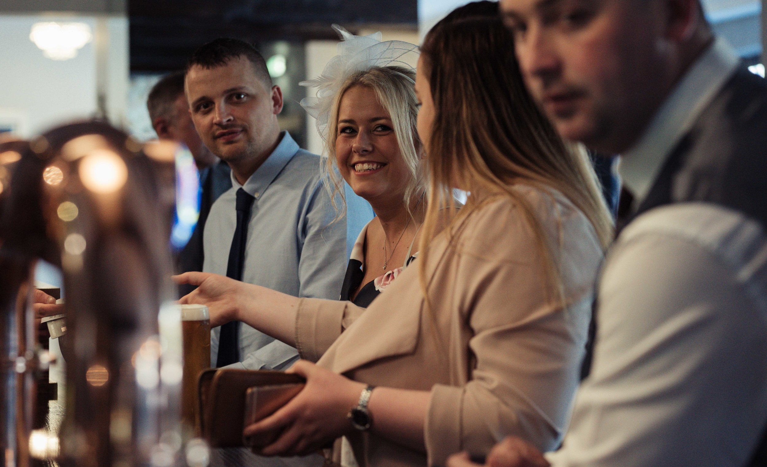 Guests stand at the bar waiting to be served, but share a smile for the camera