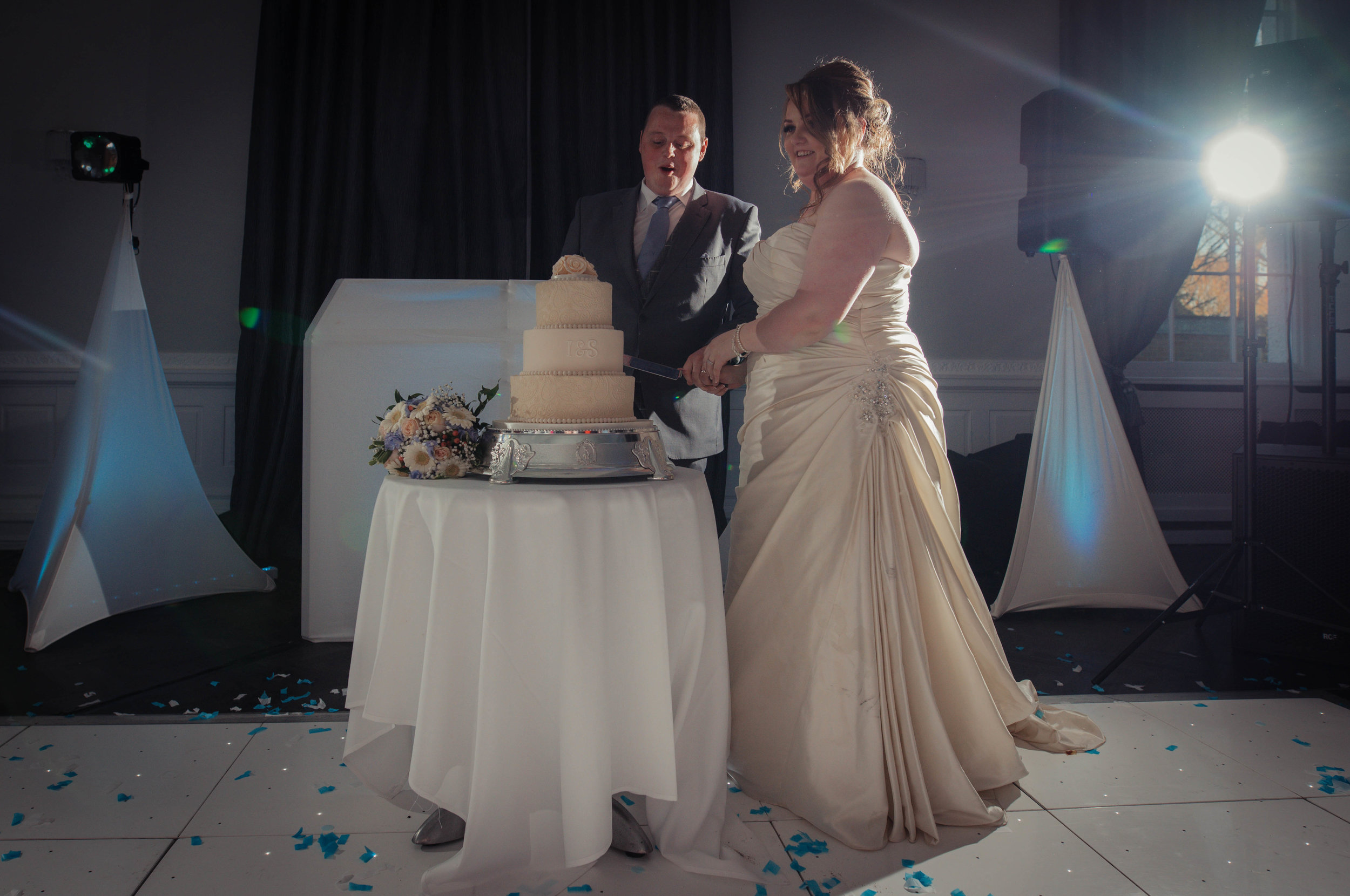 The bride and groom stand to cut their wedding cake together