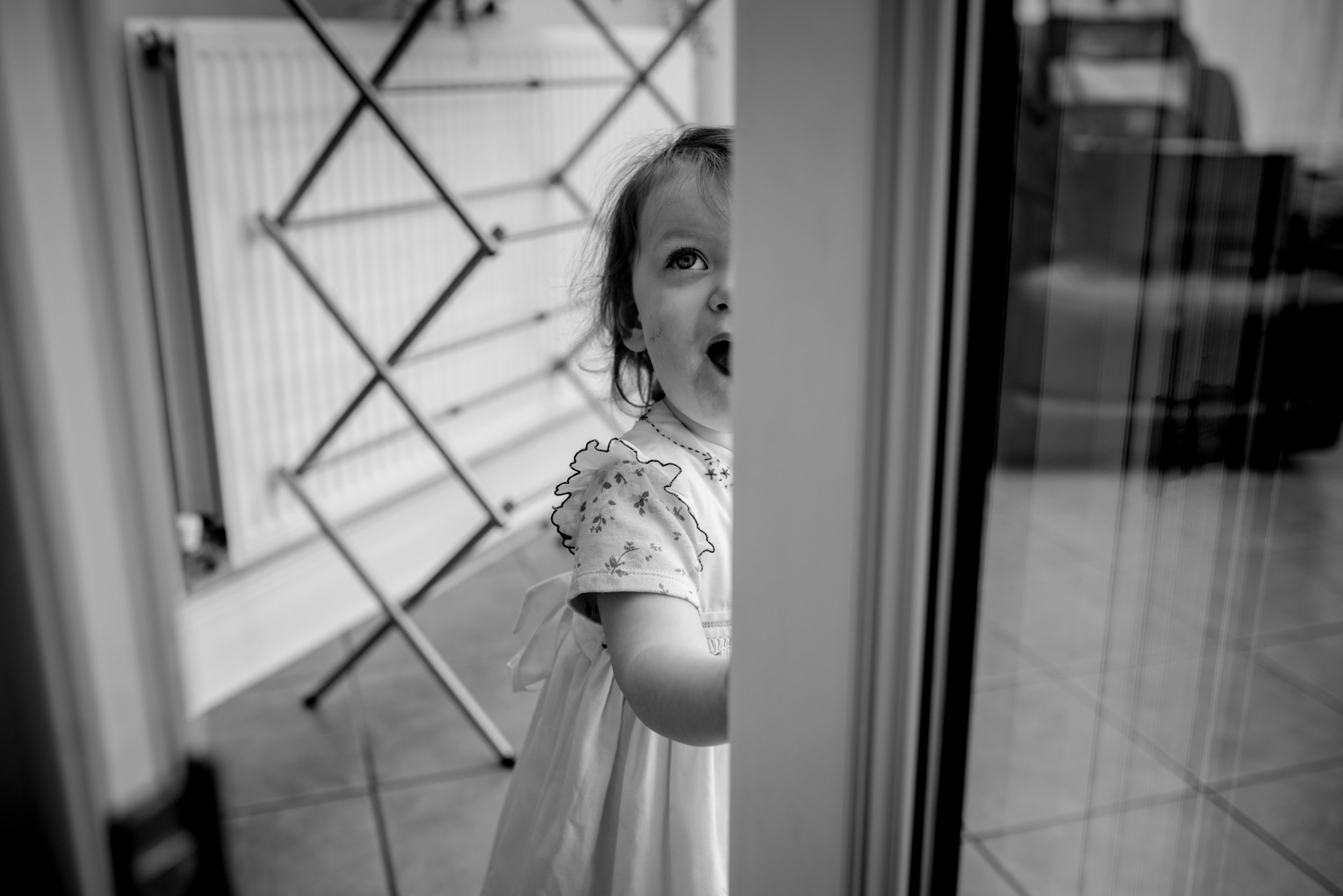 Young flower girl peeps through an open window
