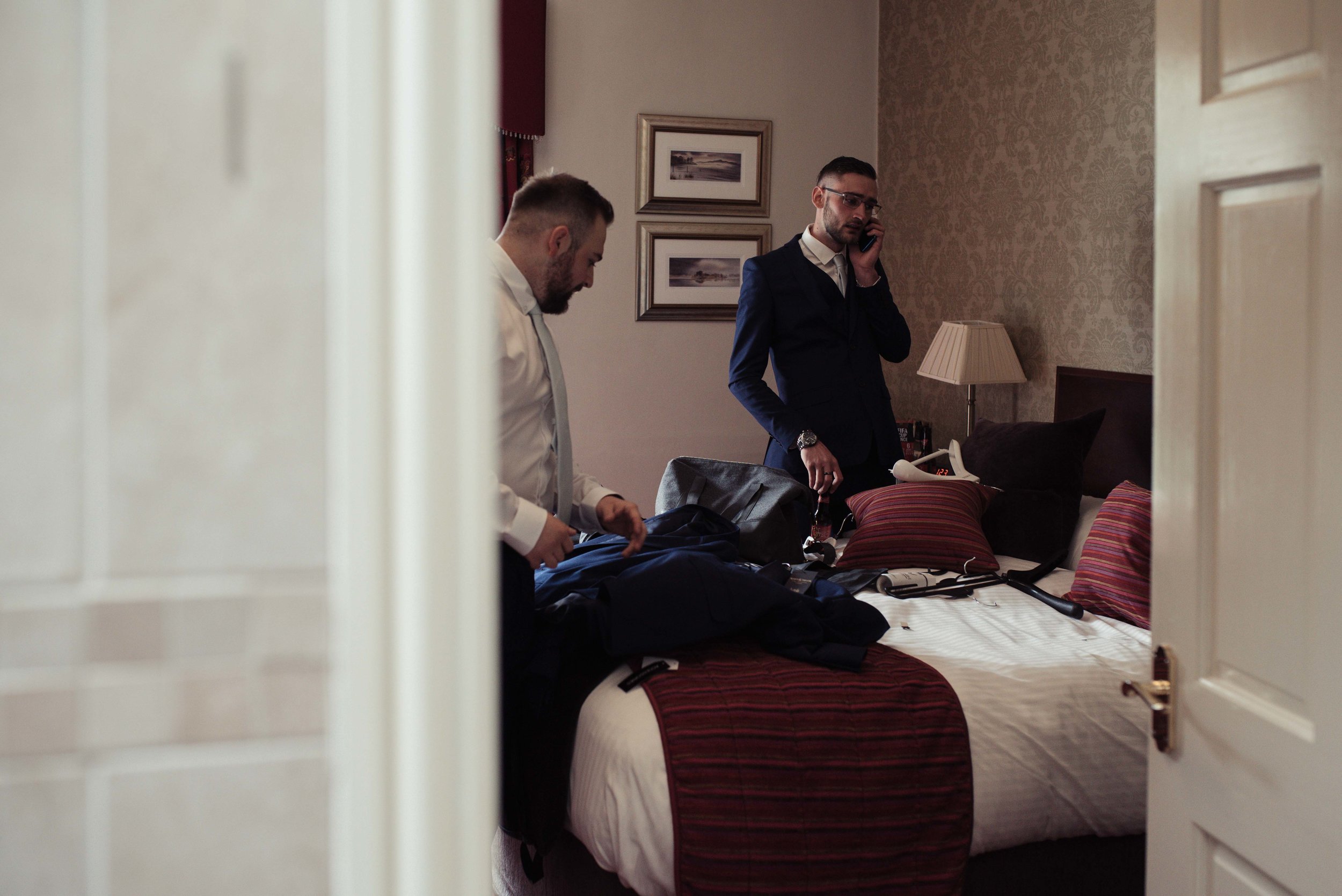 The best man makes a phone call as the groom gets ready