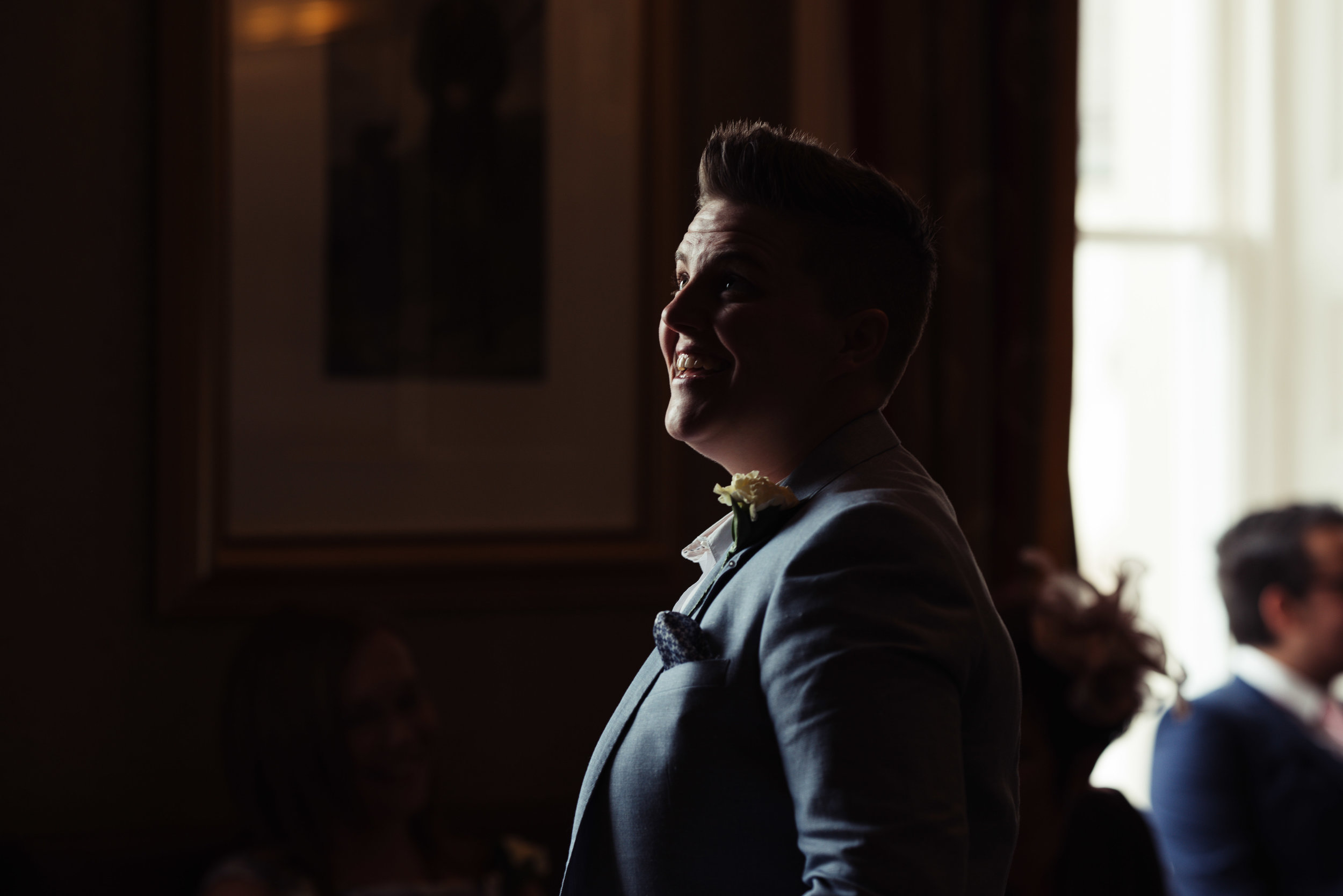 A wedding guest whose face is lit b the light coming through the window