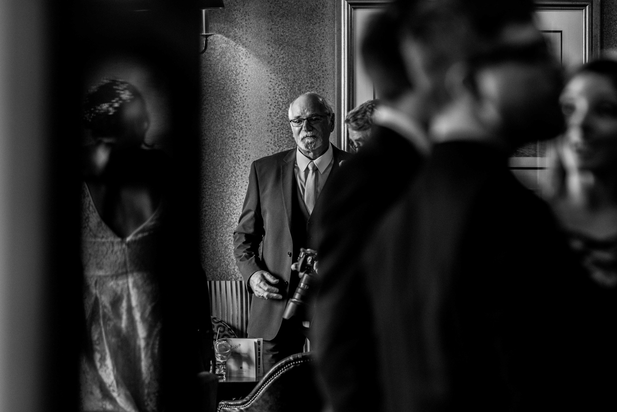 The father of the groom stands and waits for his son to come into the bar area of the wedding venue