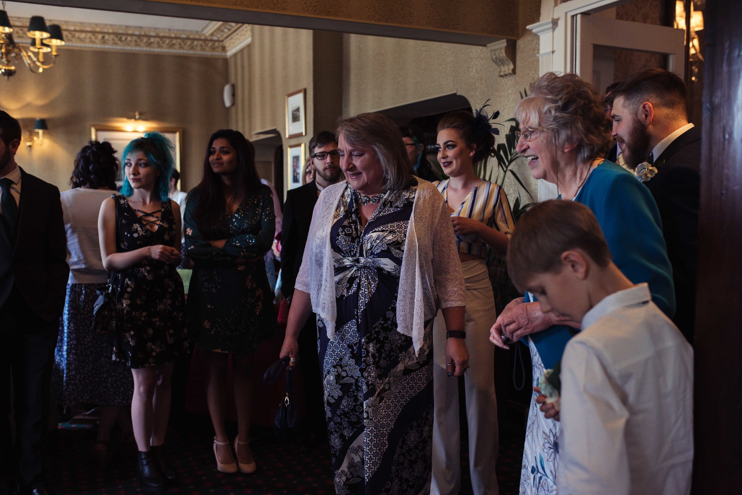 Wedding guests gather to see the groom in his suit for the first time