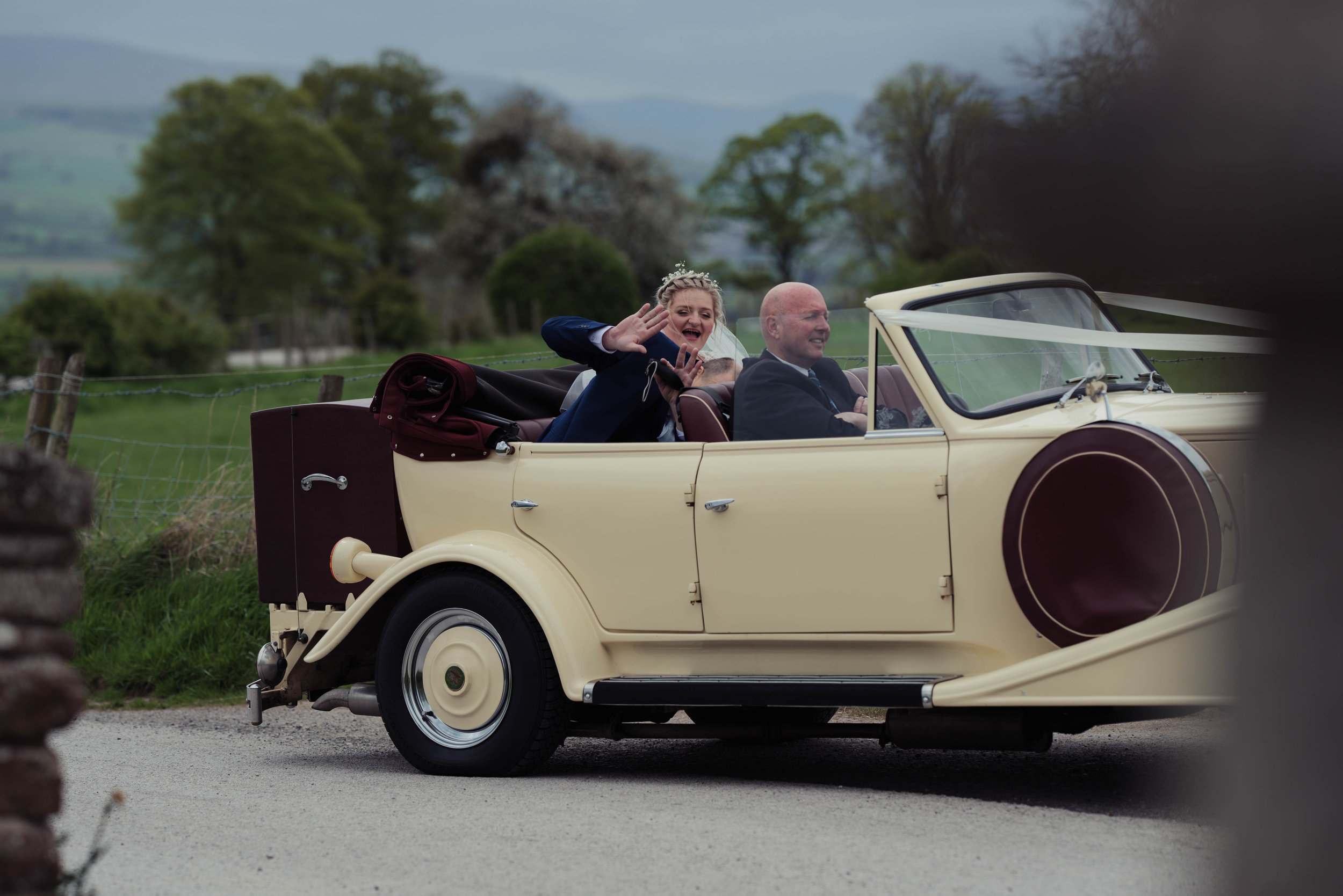 The bride and groom arrive at the wedding venue in a vintage car