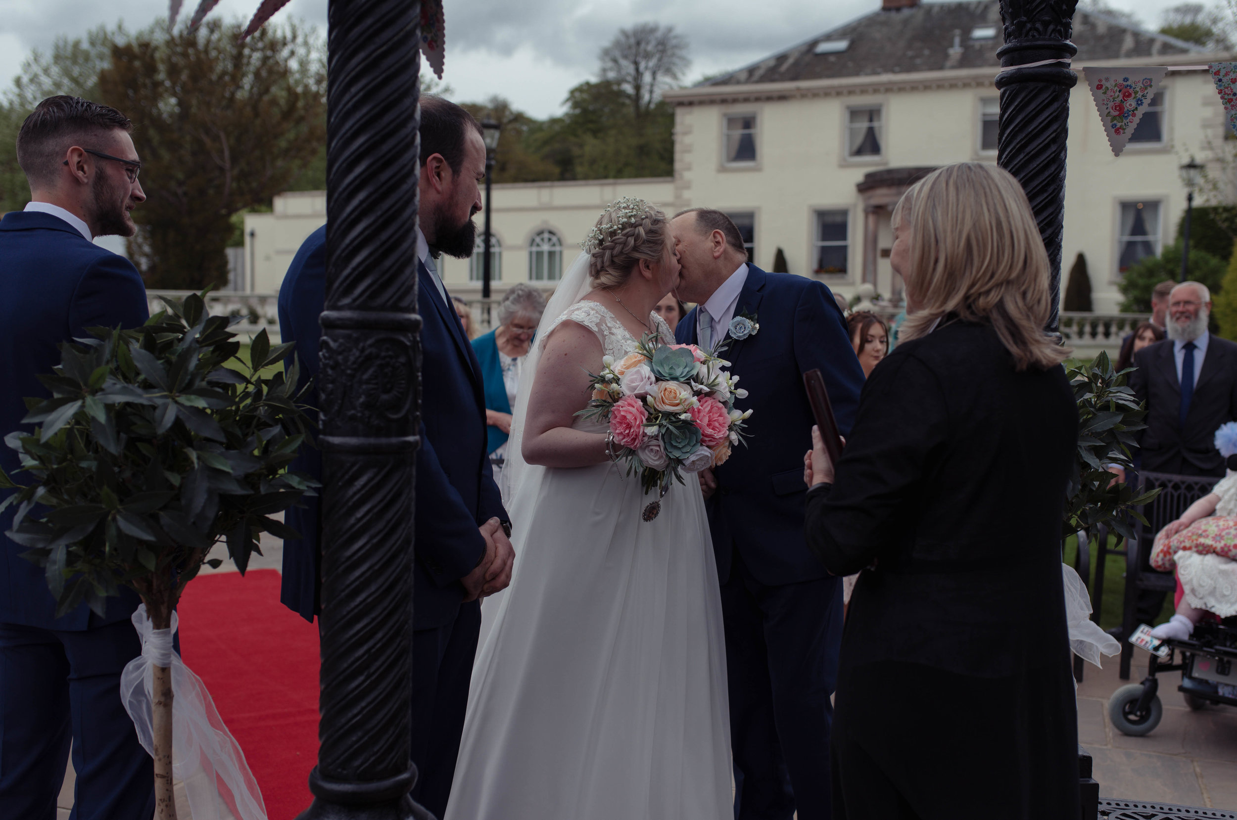 The bride and her father share a kiss as she gives him away