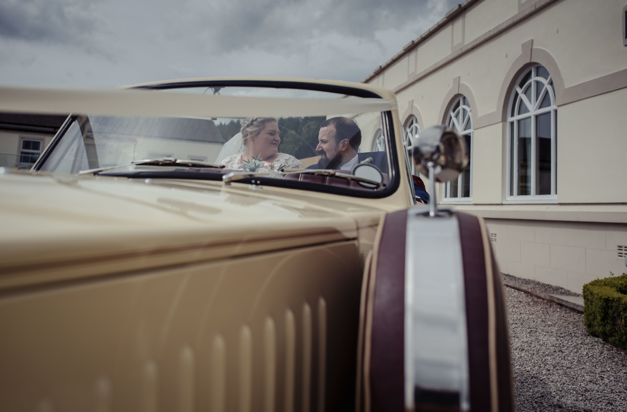 The bride and groom sit and share a moment alone together in their wedding car