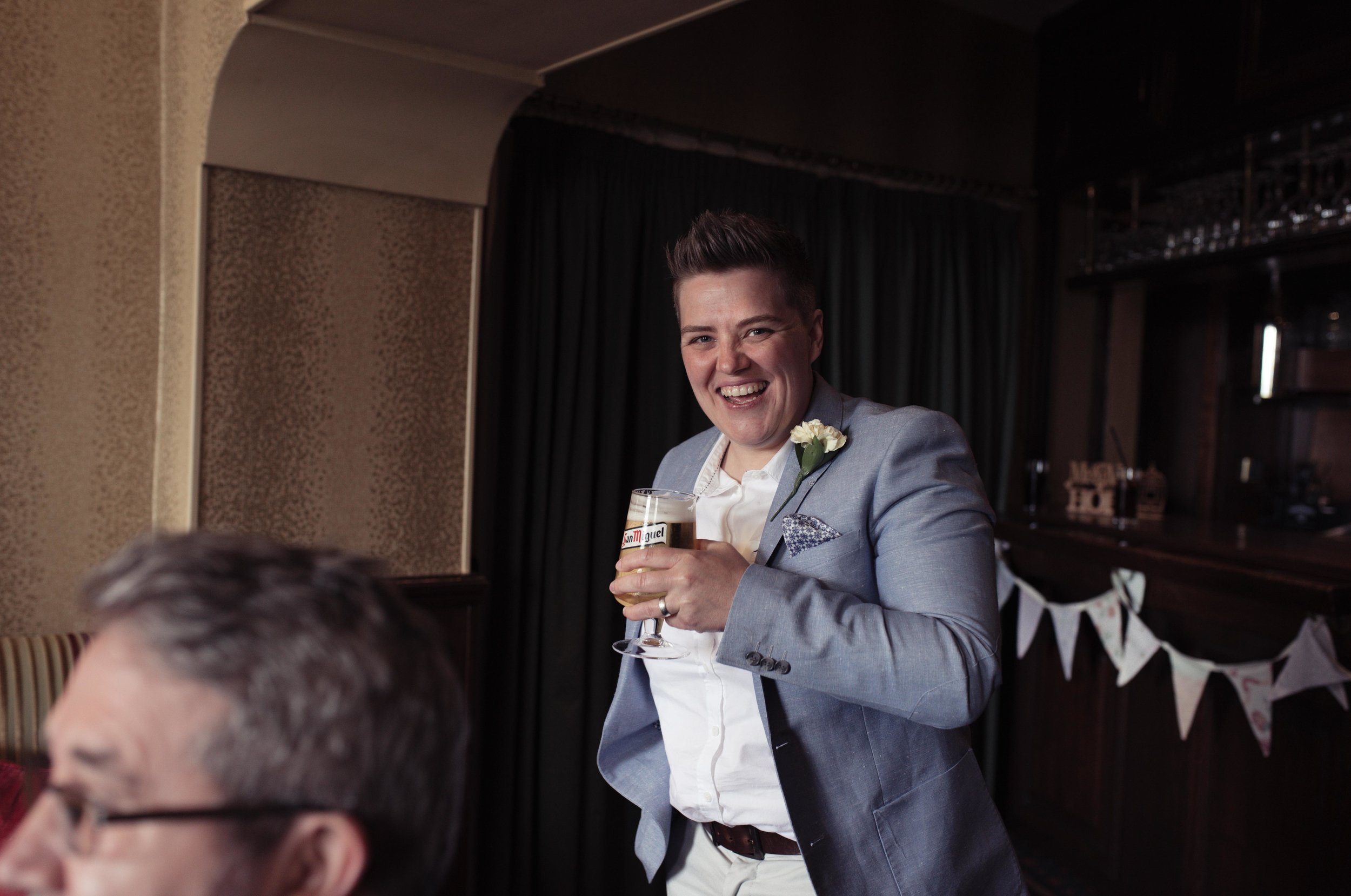 A wedding guest has a massive smile on her face in the bar of the wedding venue