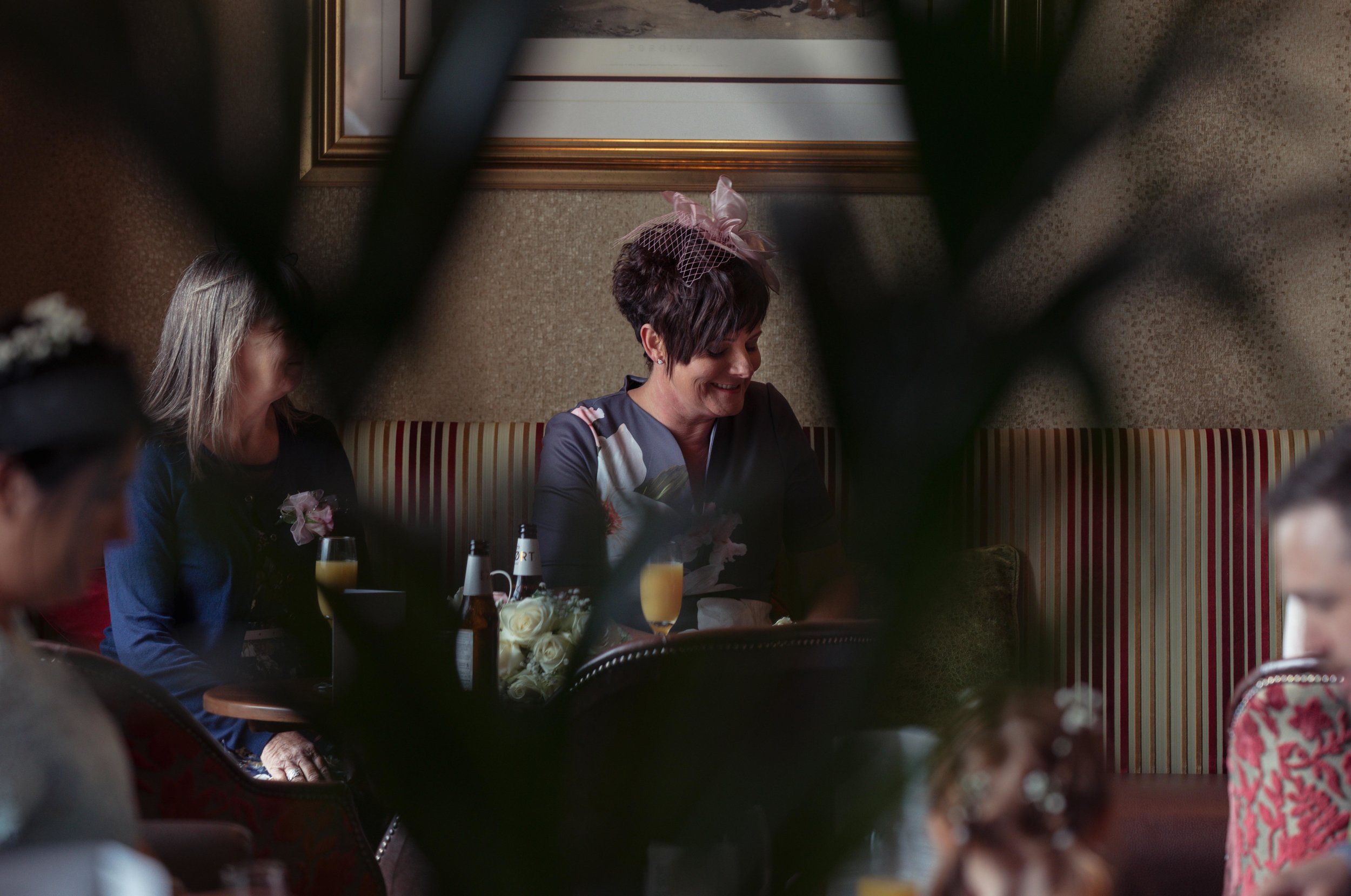 A wedding guest sits and chats to her friends in the sofa in the wedding venue