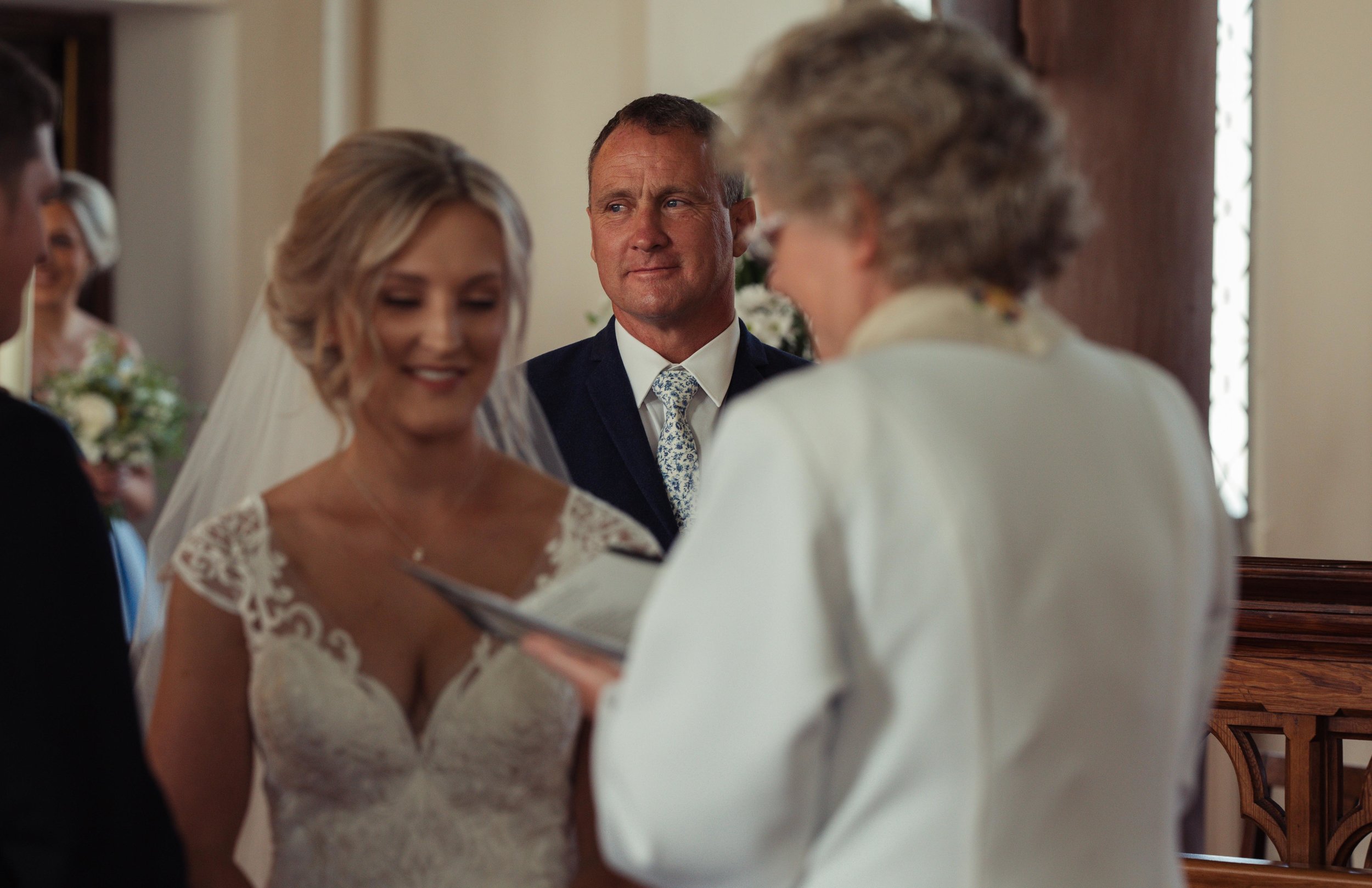 the bride smiles before she picks up her ring to give to the groom