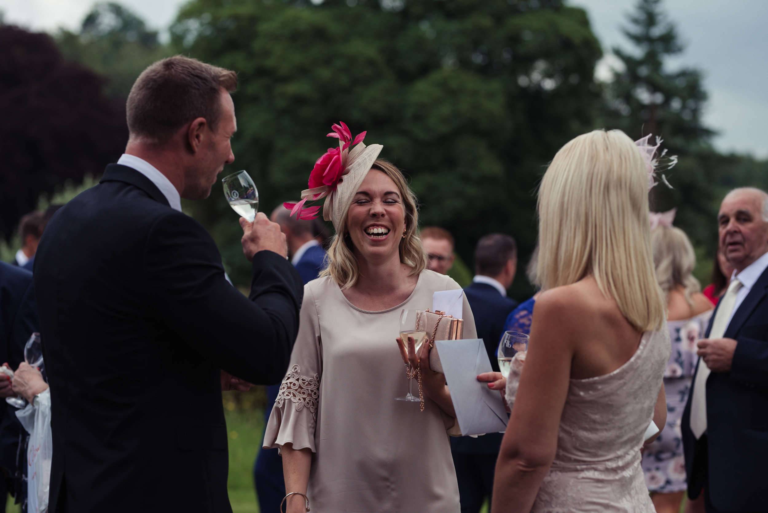 A wedding guest has a giggle with members of her group during the drinks reception