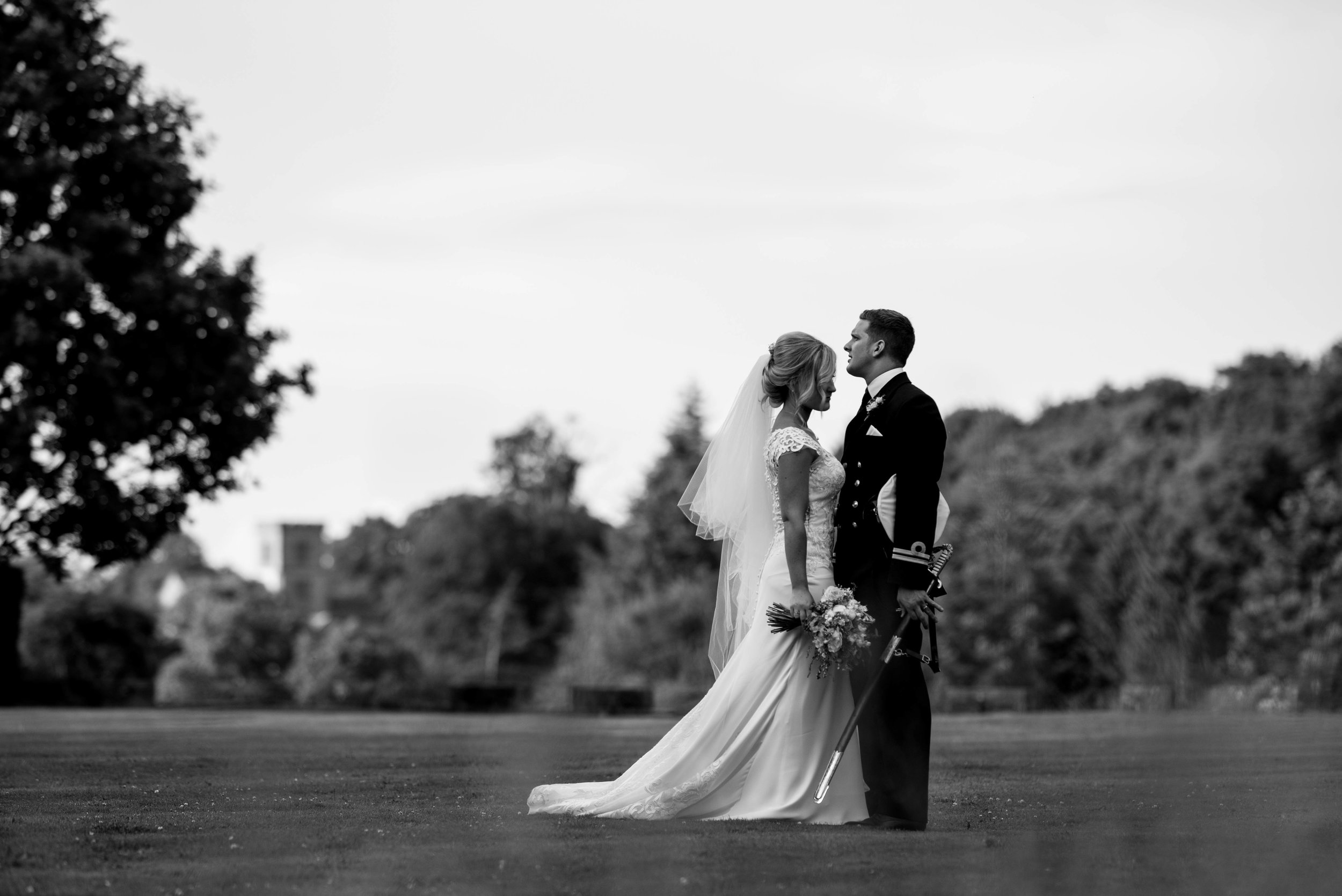 The bride and groom stand together with sword and flowers in hand and chat to each other