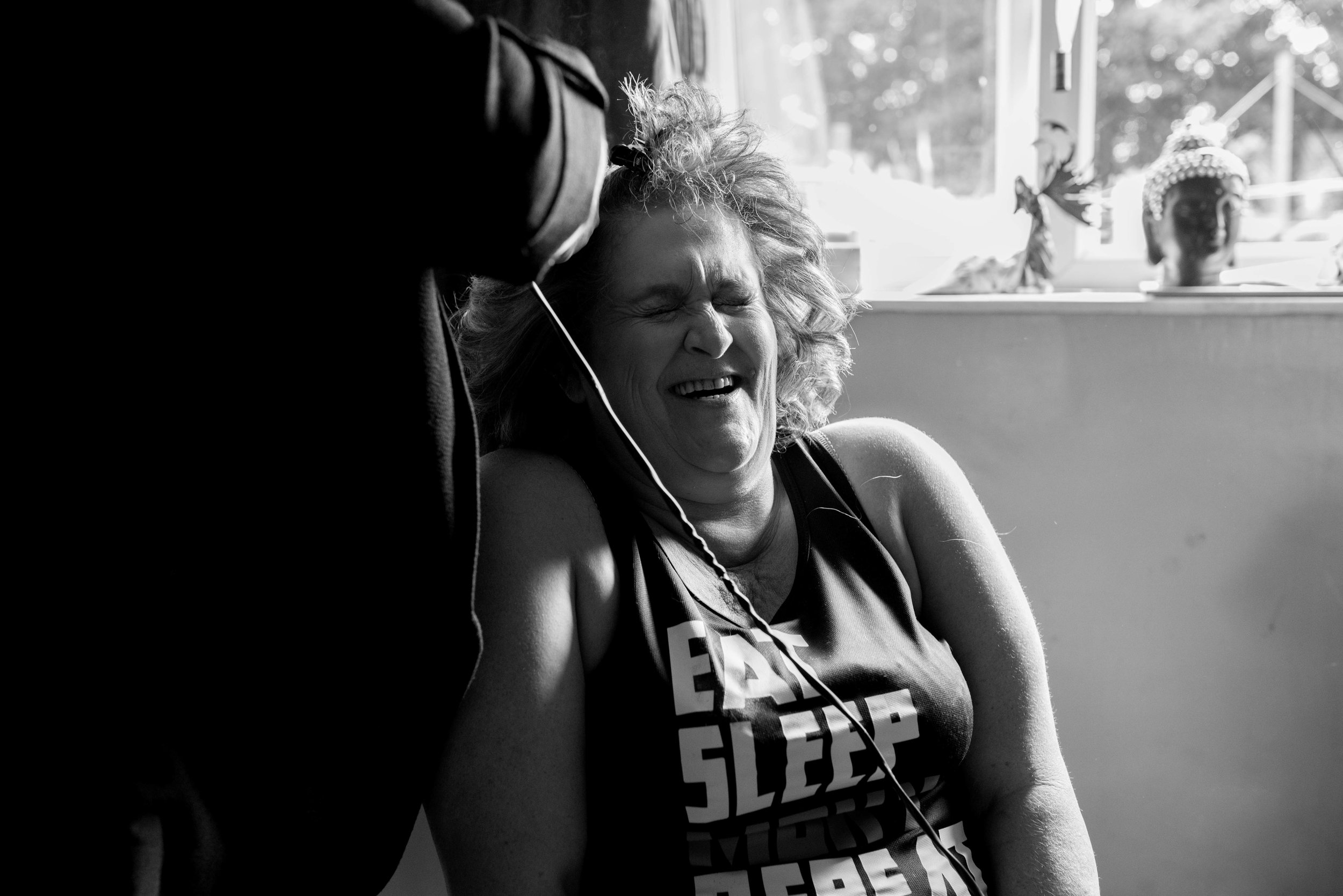Curly haired bride laughs her head off while she's getting her hair ready for the wedding