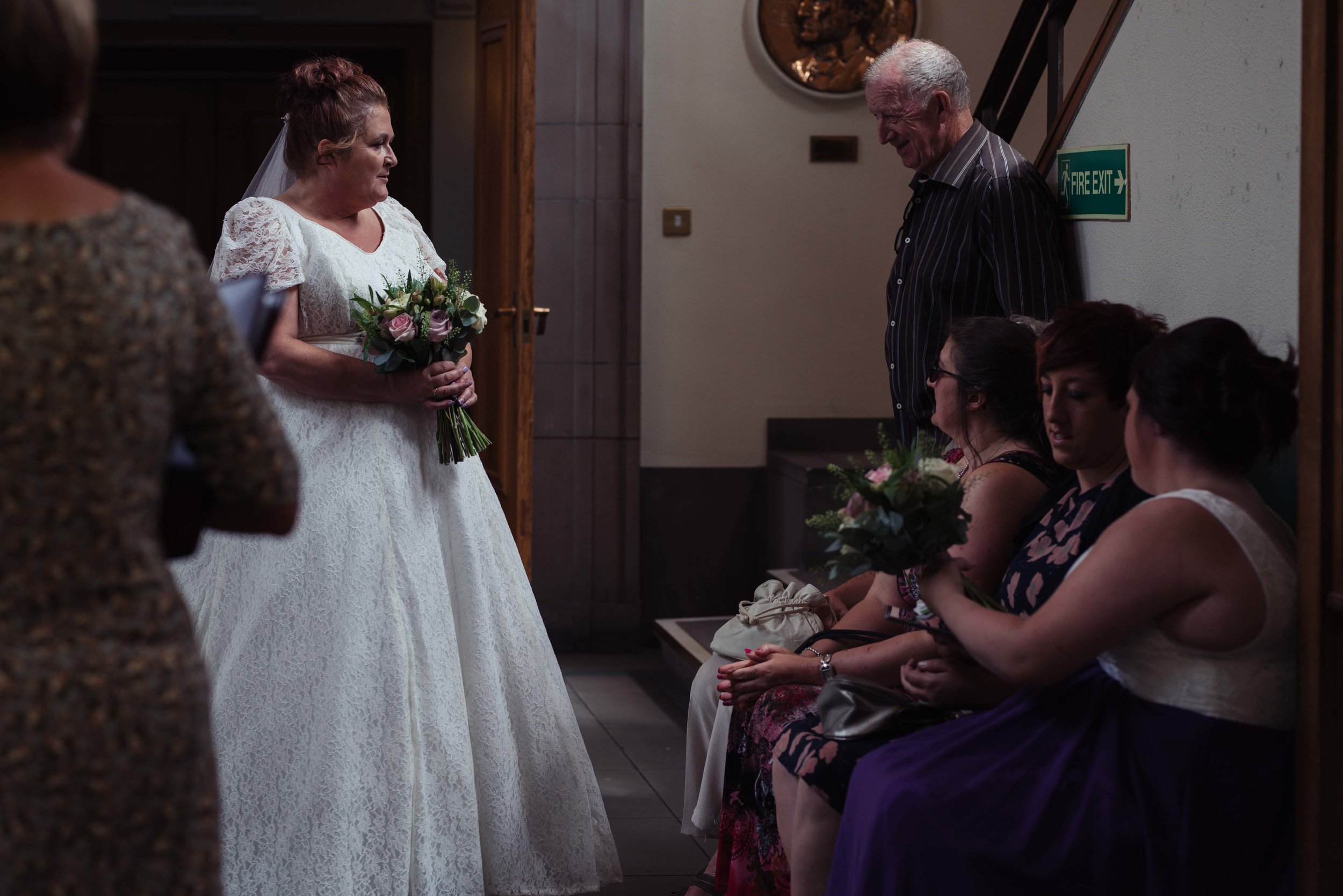 The bride chats to guests as she waits outside the wedding ceremony room