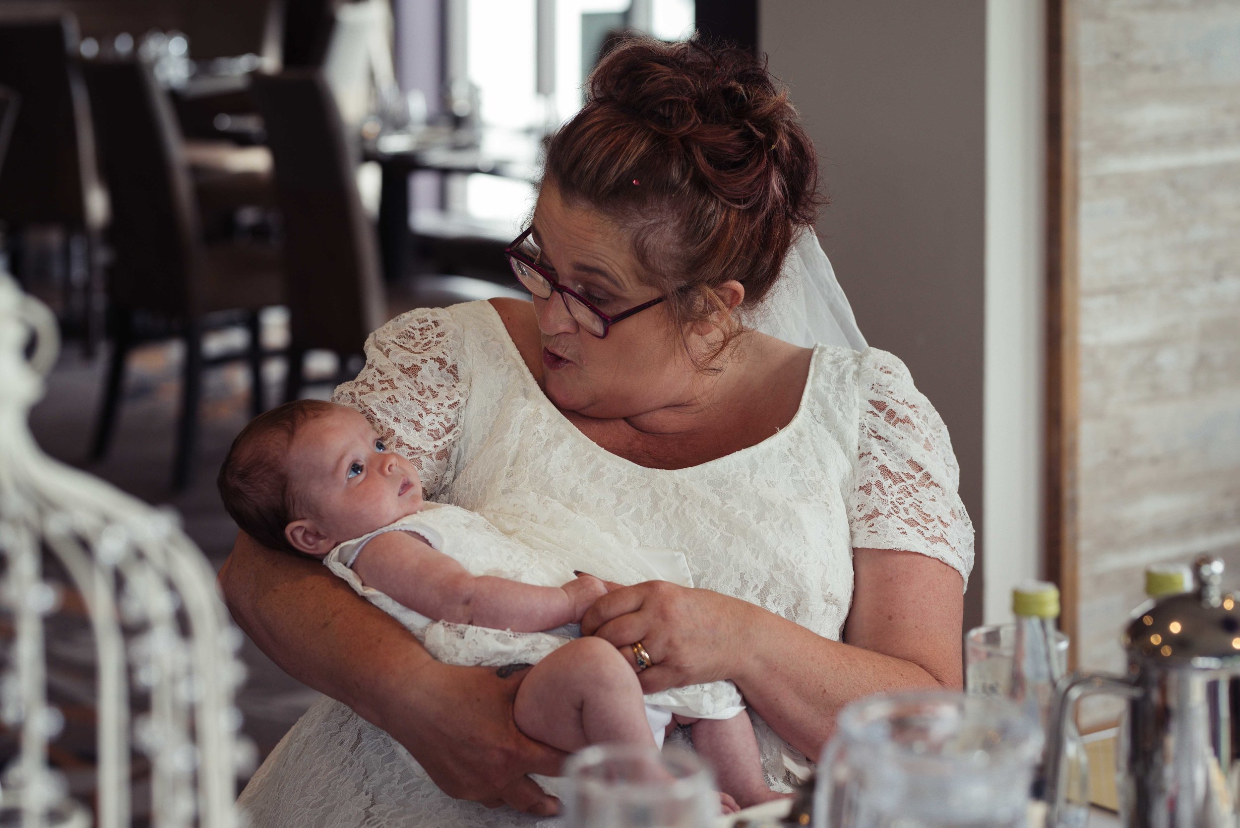 The bride holds a newborn baby wedding guest