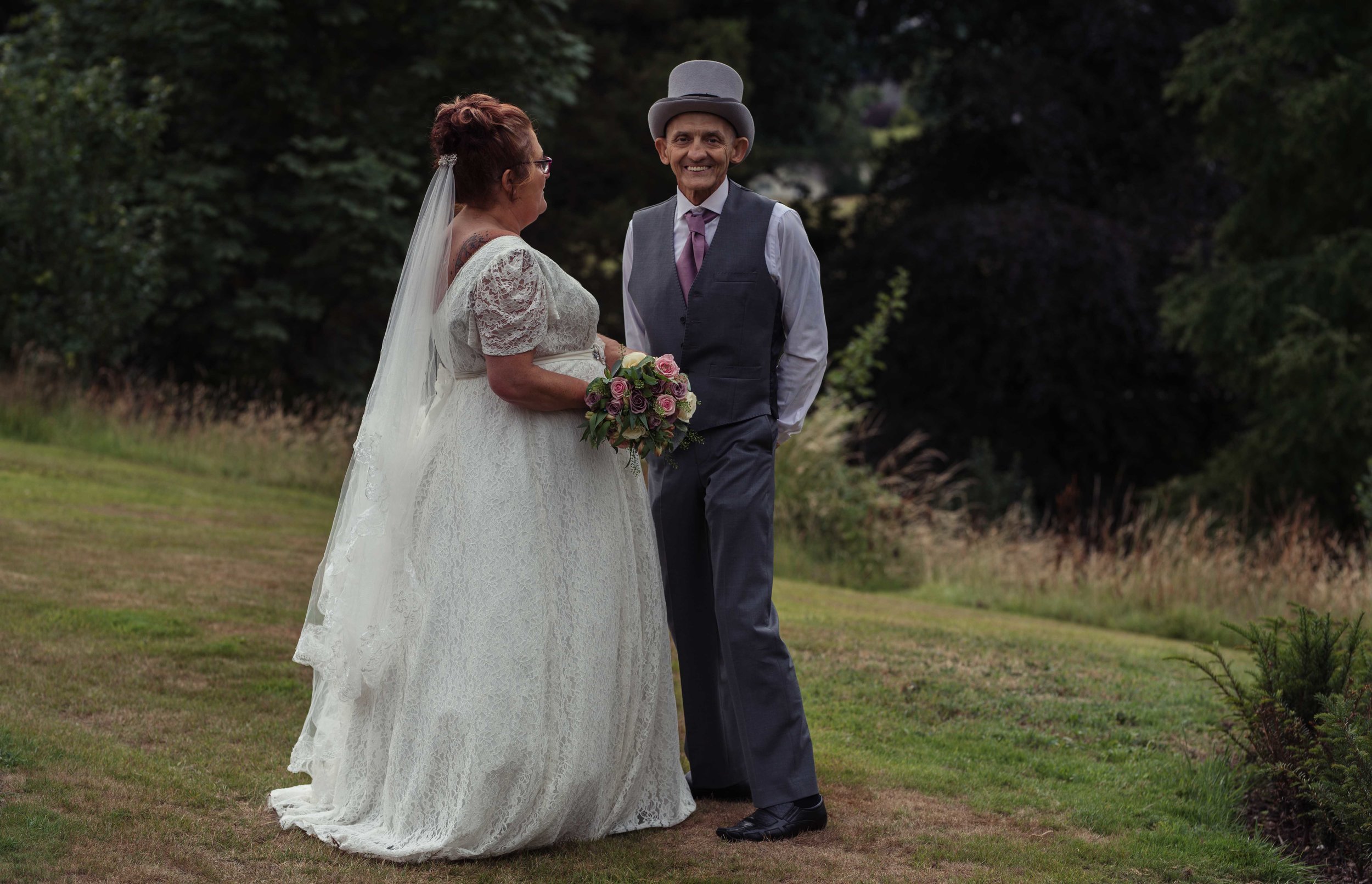 The groom giggles towards the camera as they stand for their Cumbria wedding photography