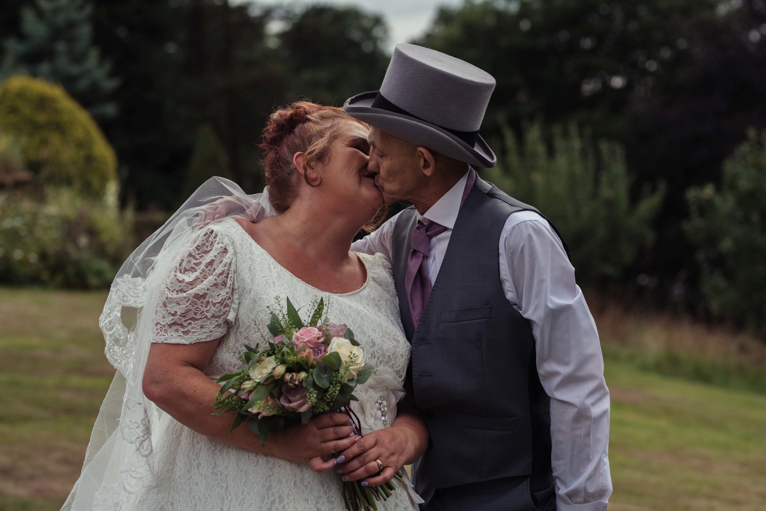 The bride and groom share a kiss together in the grounds of the castle green hotel