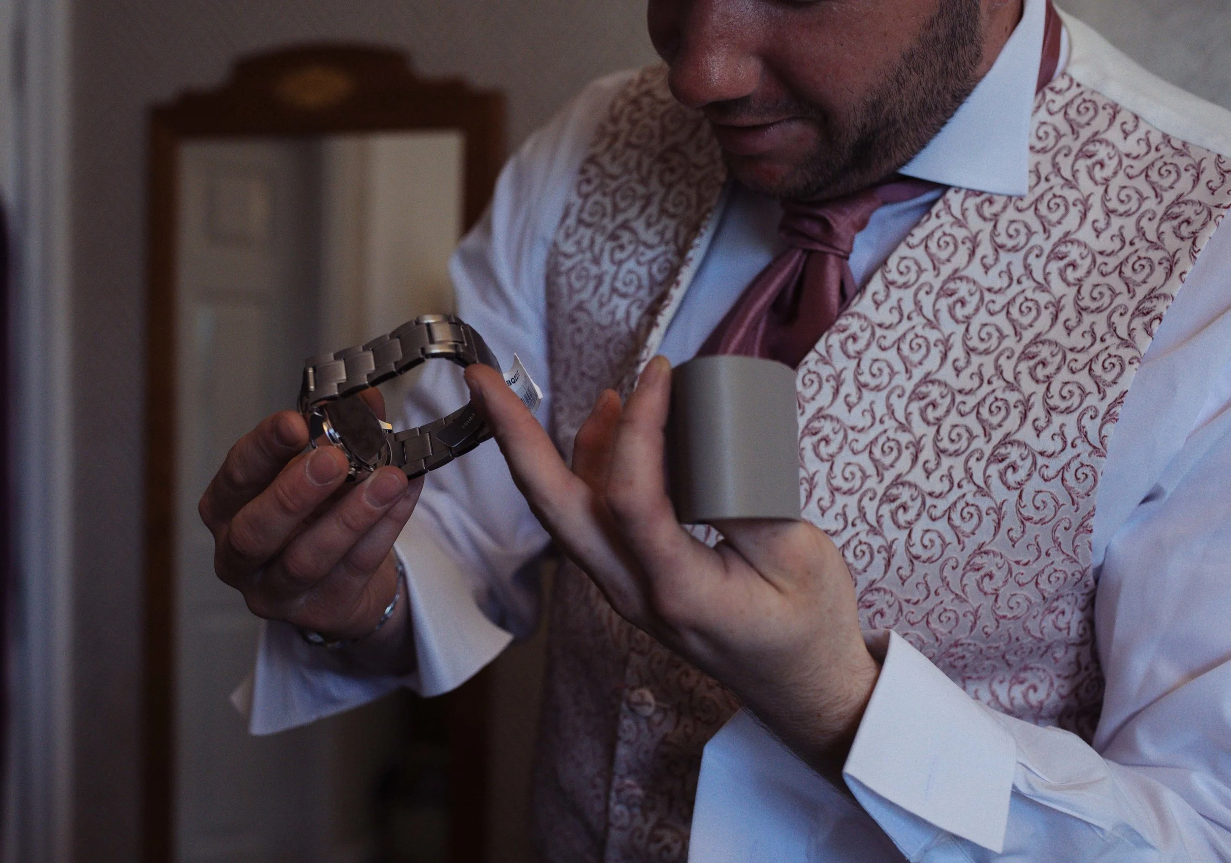 Close up of the groom looking at his watch, a present from his bride