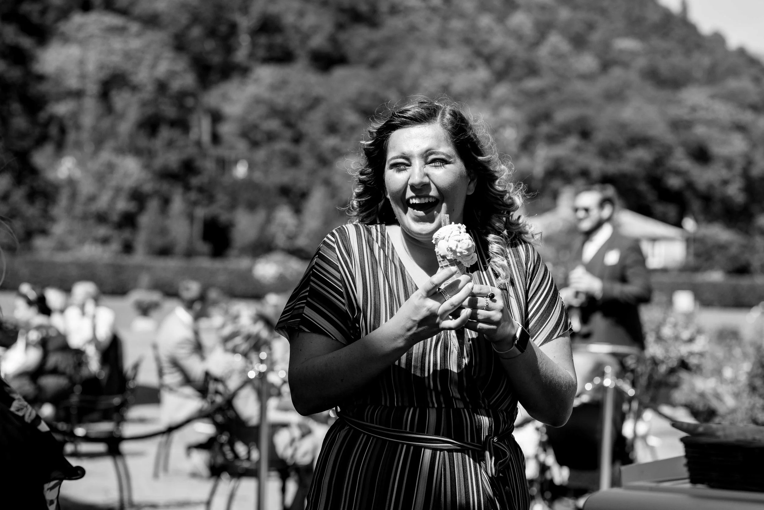 One of the wedding guests laughs out loud as she eats her ice cream