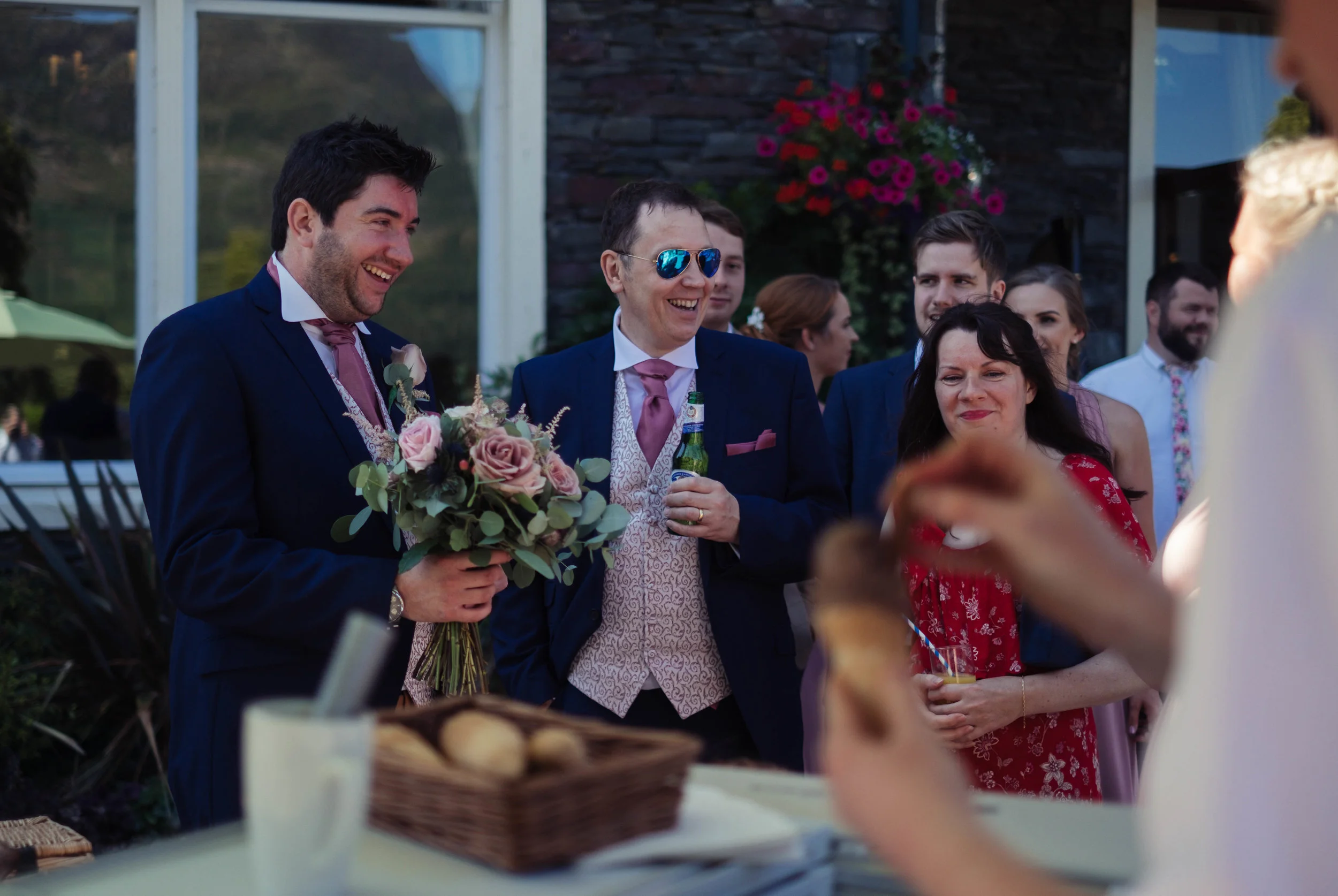 The groom holds the bridesmaids flowers as she gets an ice cream at the inn on the lake