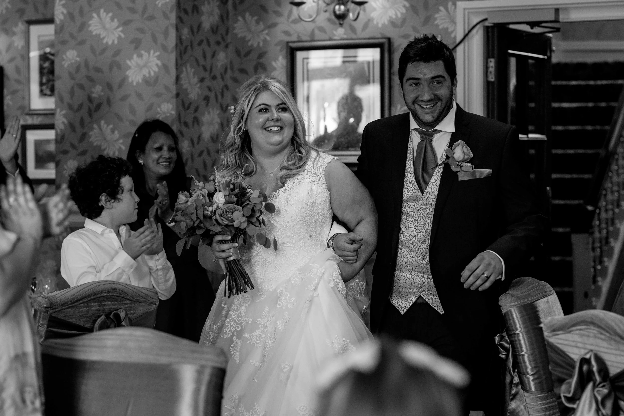 The bride and groom make their way into the wedding breakfast room at the inn on the lake