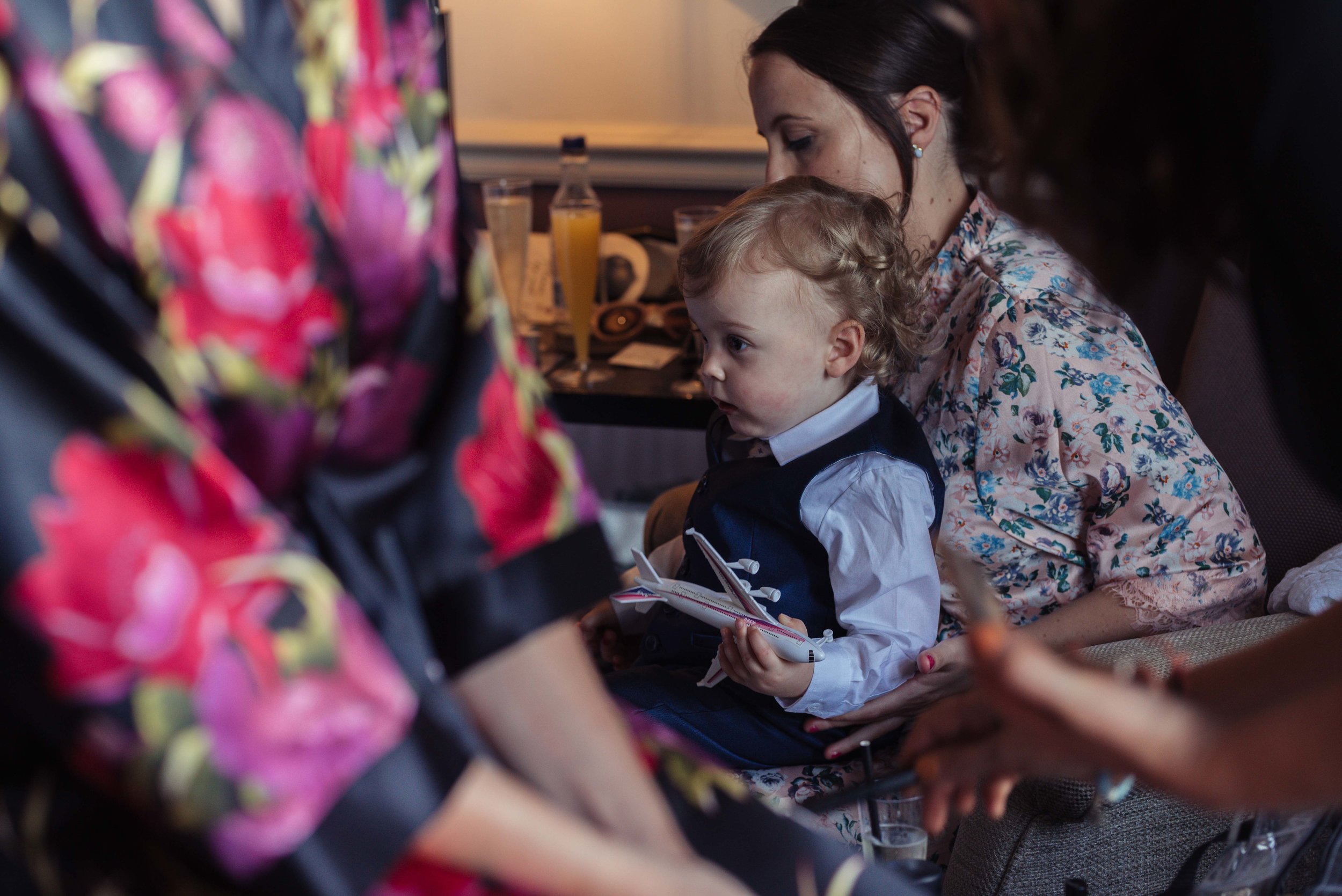 A bridesmaid sits with her son, the page boy, on her knee