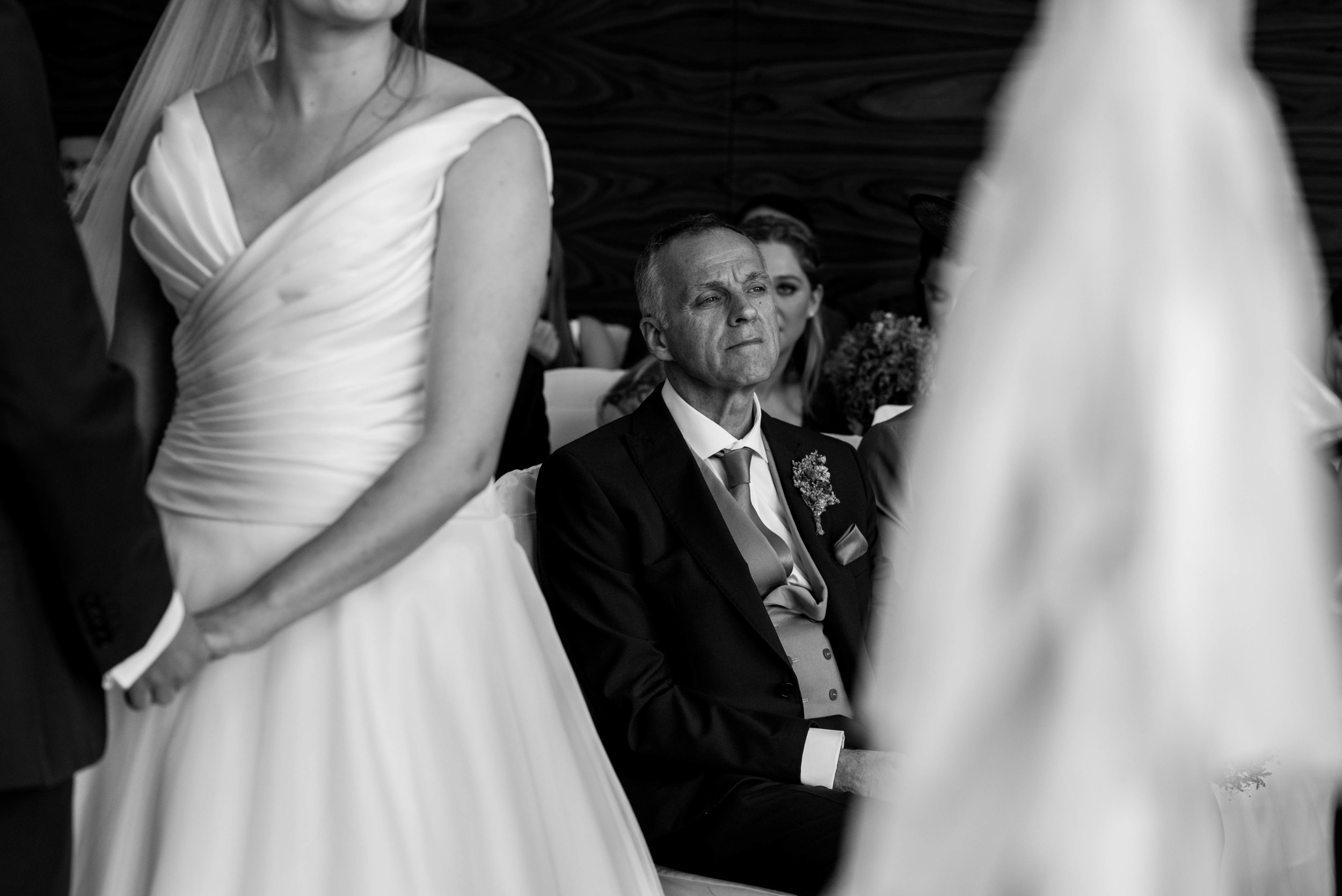 The brides father sits looking emotional during the wedding ceremony