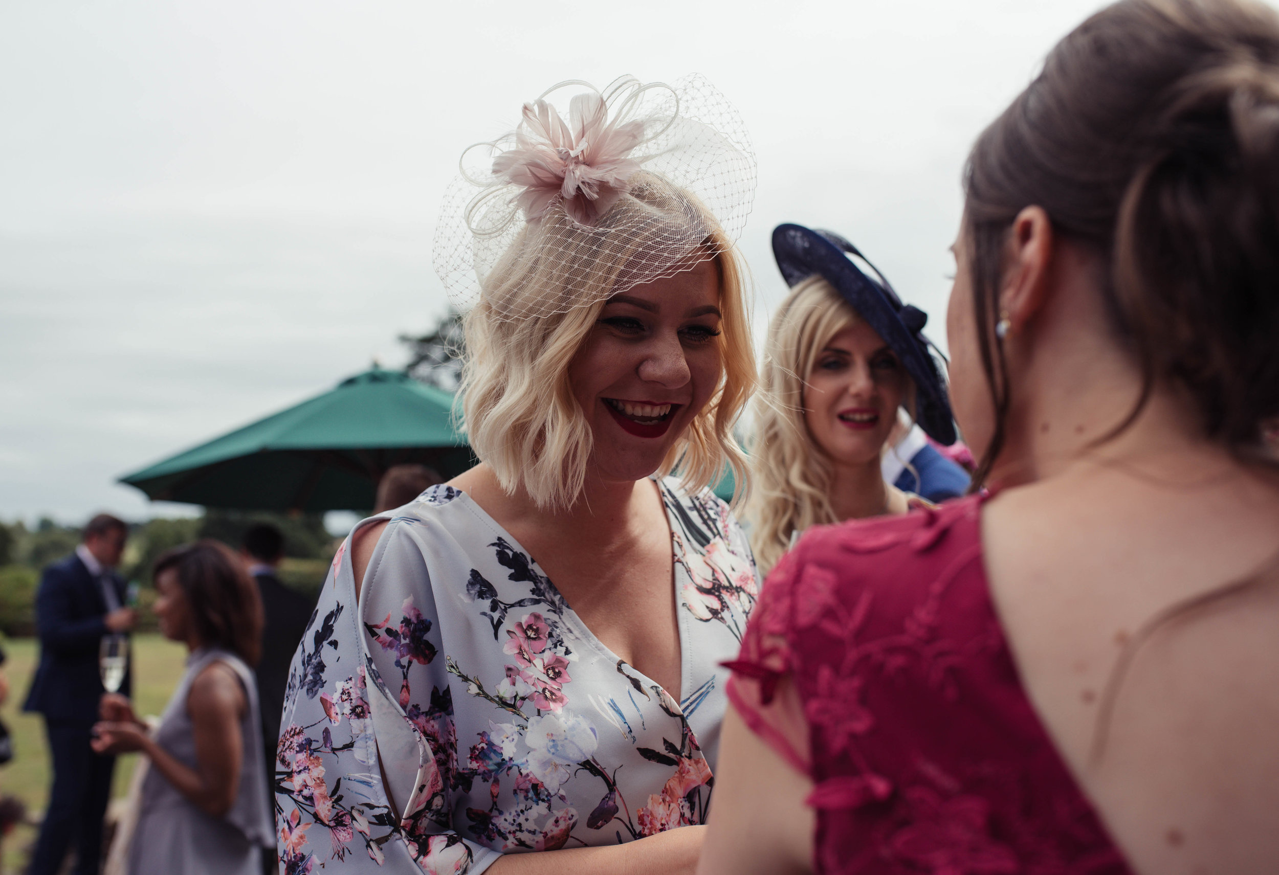 A wedding guest with a floral dress chats to one of the bridesmaids