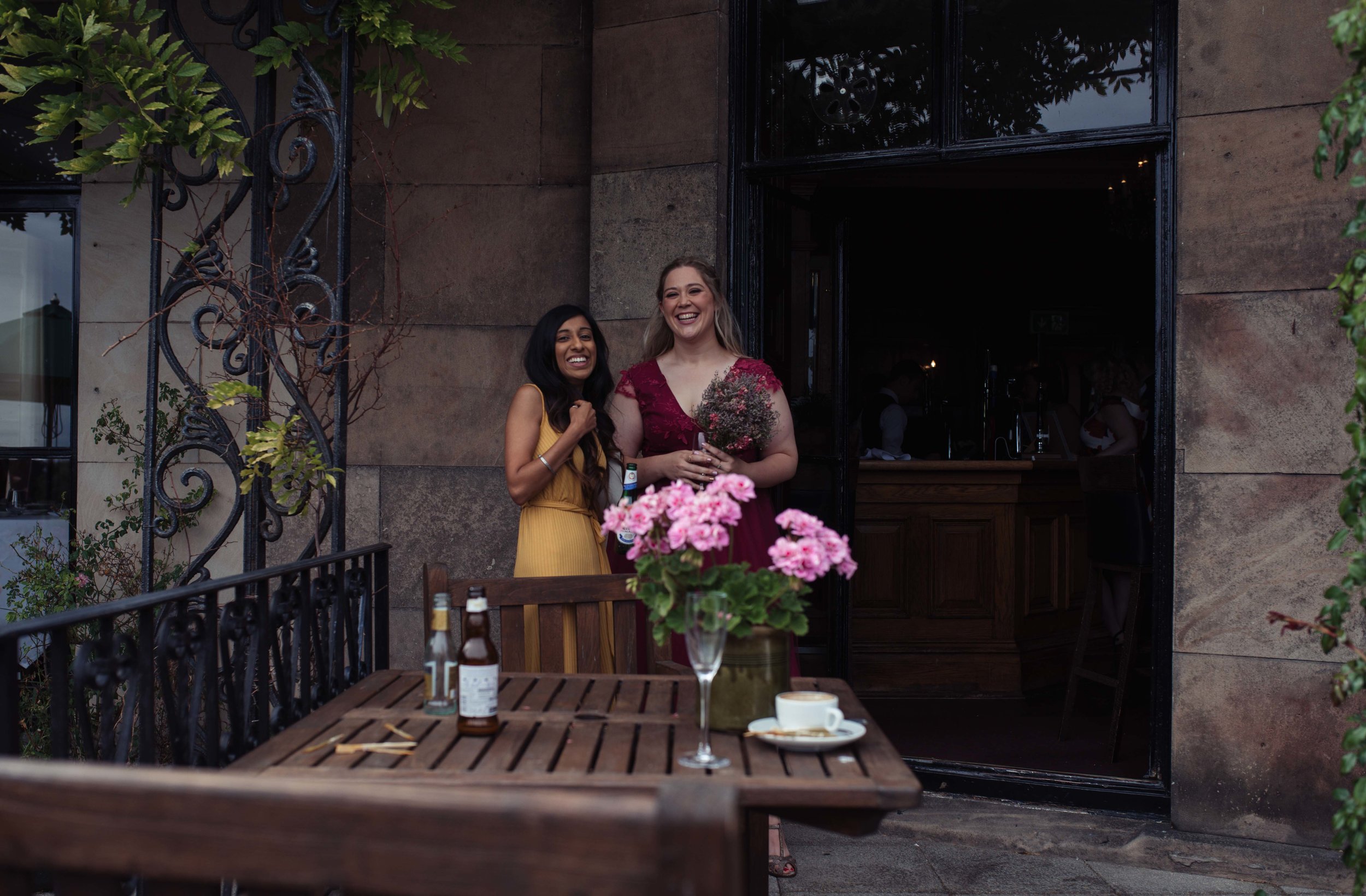 Two wedding guests stand chatting outside rookery hall