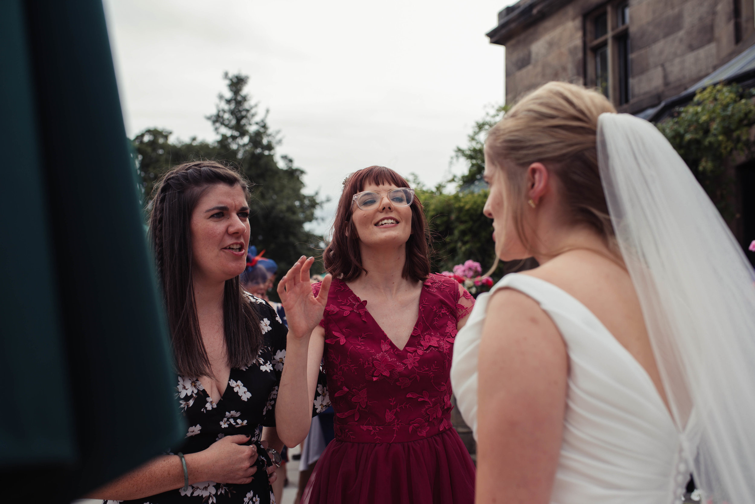 A bridesmaid has a laugh with the bride outside rookery hall