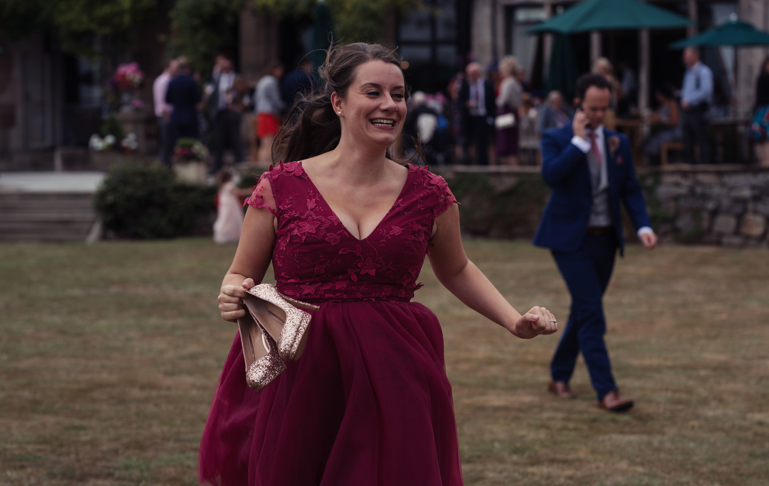 The bridesmaid runs towards the other bridesmaids with her shoes off