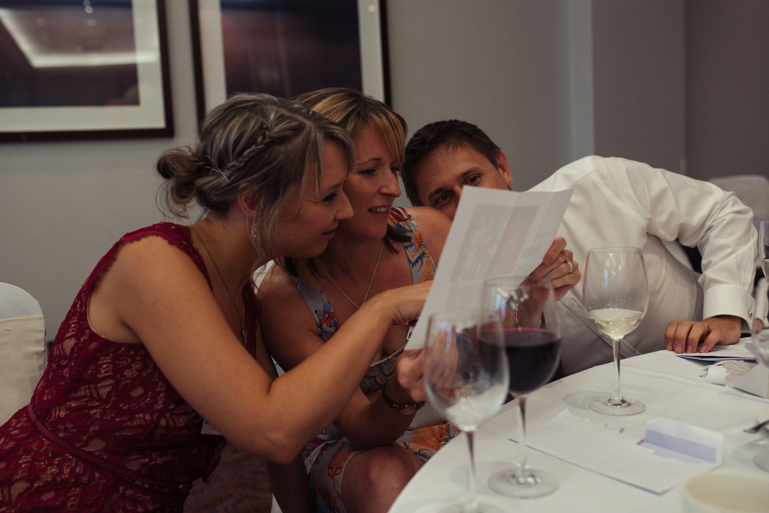 Wedding guests looking at reading material provided by the best man during his speech